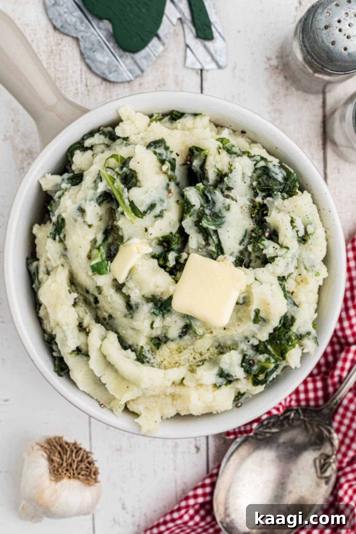 Overhead shot of a bowl of traditional colcannon, a classic Irish mashed potato dish with kale or cabbage and a dollop of melting butter in the center.