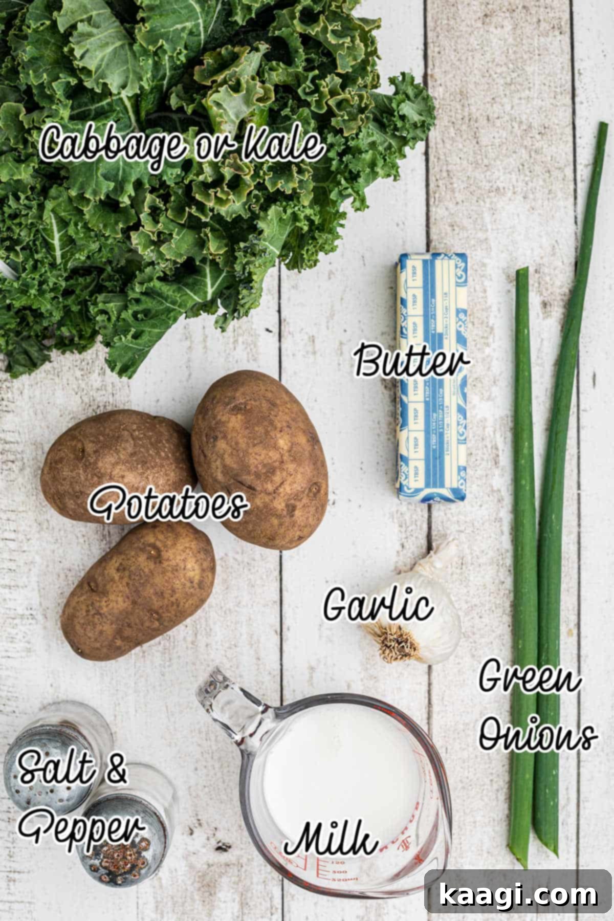 Ingredients for traditional colcannon laid out, including russet potatoes, kale, garlic, milk, butter, salt, pepper, and green onions.