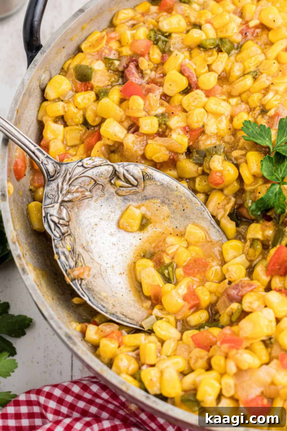 Close up side angle shot of a skillet with cajun corn maque choux and a spoon digging in.