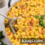 Close up of some cajun corn maque choux with a big spoon digging in.