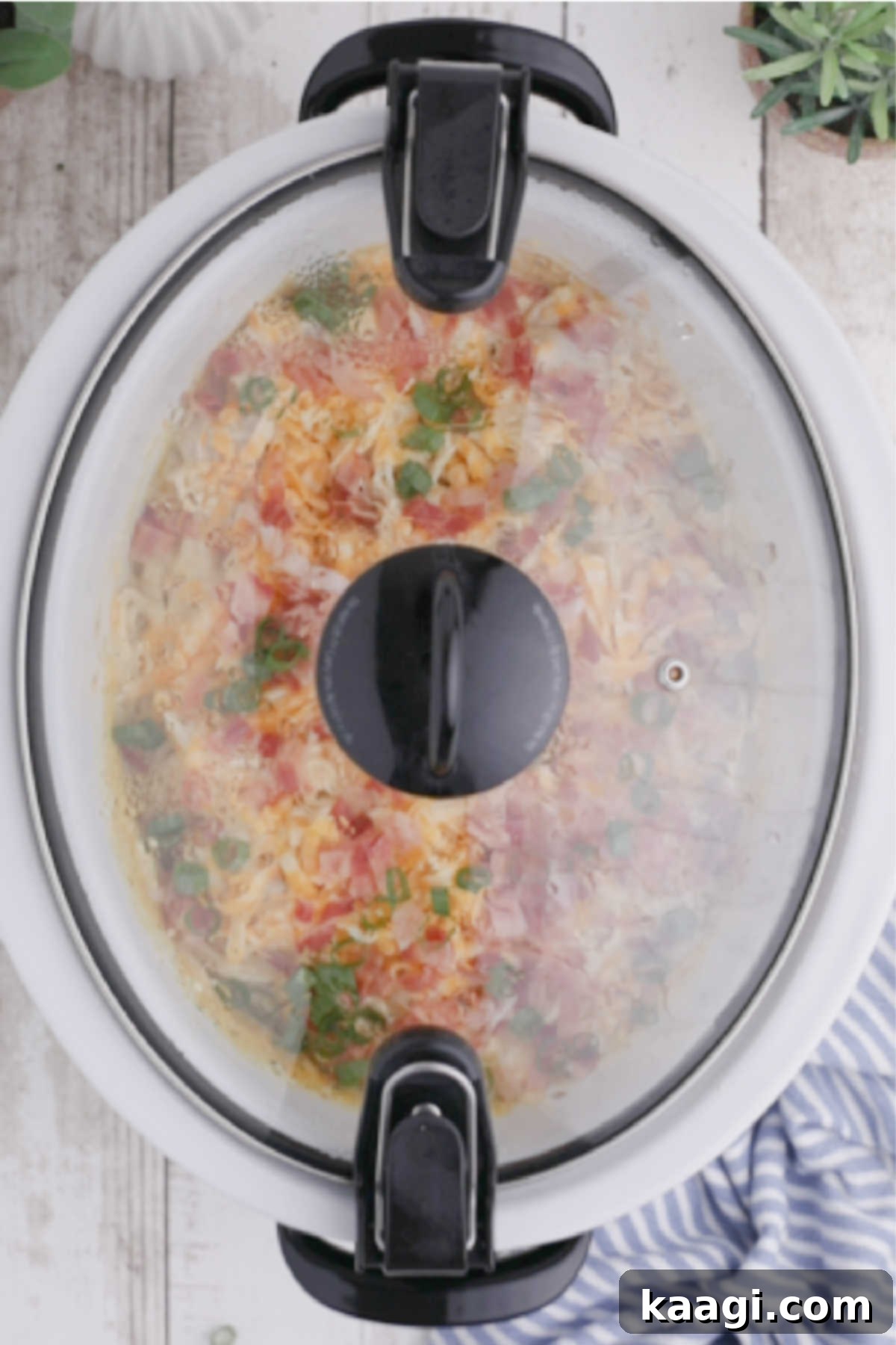 Creamy Slow Cooker Ranch Chicken Spaghetti 13 A closed crock pot containing the fully cooked ranch chicken spaghetti, with garnishes added and cheese melted, indicating the final stage before serving.