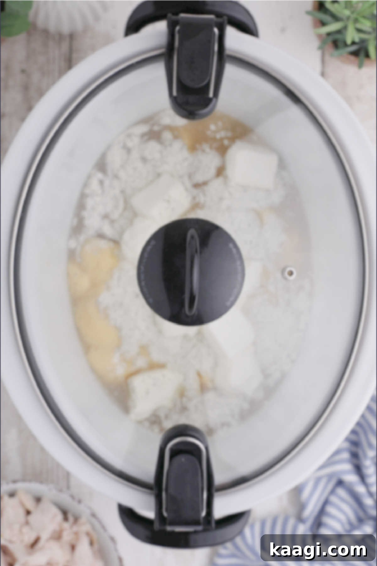 Creamy Slow Cooker Ranch Chicken Spaghetti 6 A lidded crock pot, showcasing the initial ingredients settled inside and ready to begin the slow cooking process.