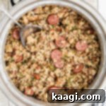 Overhead shot of a rice cooker jambalaya with a spoon digging in, cropped square.