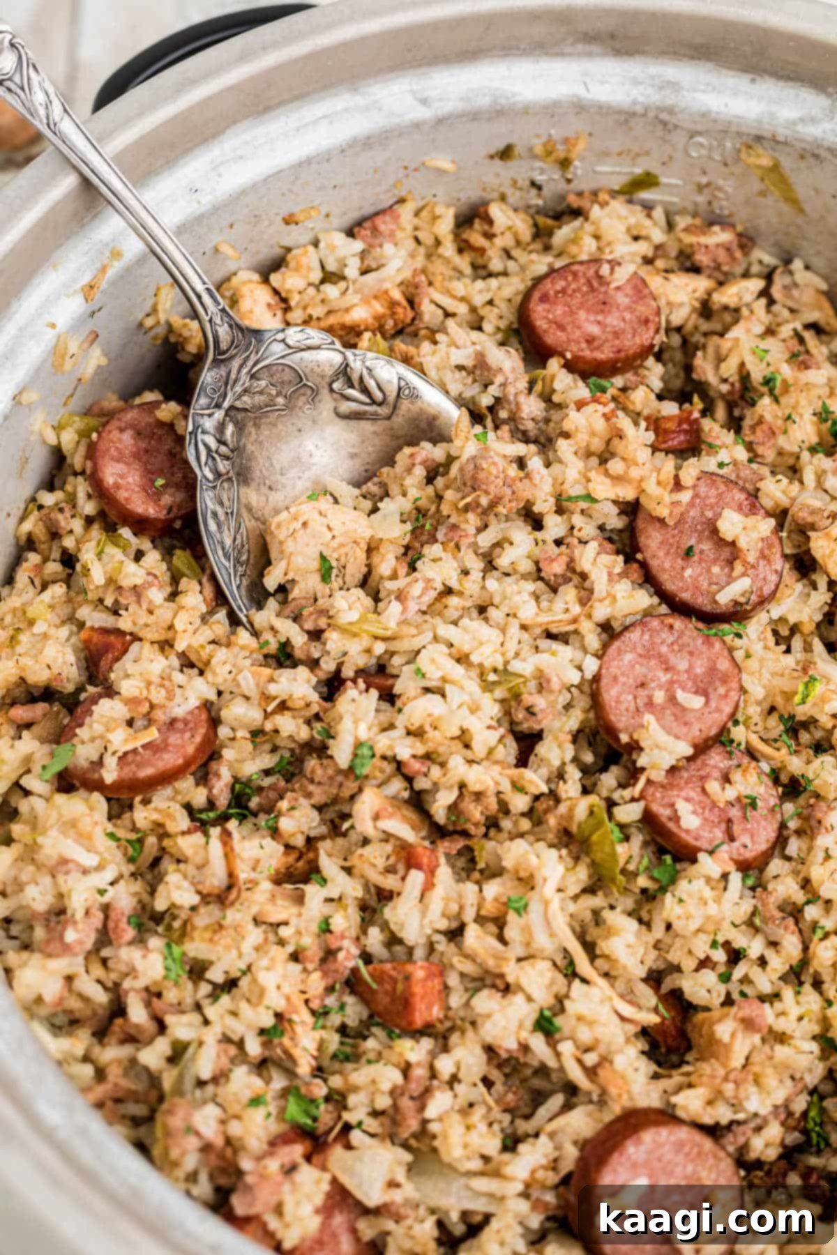 Close up side shot of a rice cooker with jambalaya and a spoon digging in.