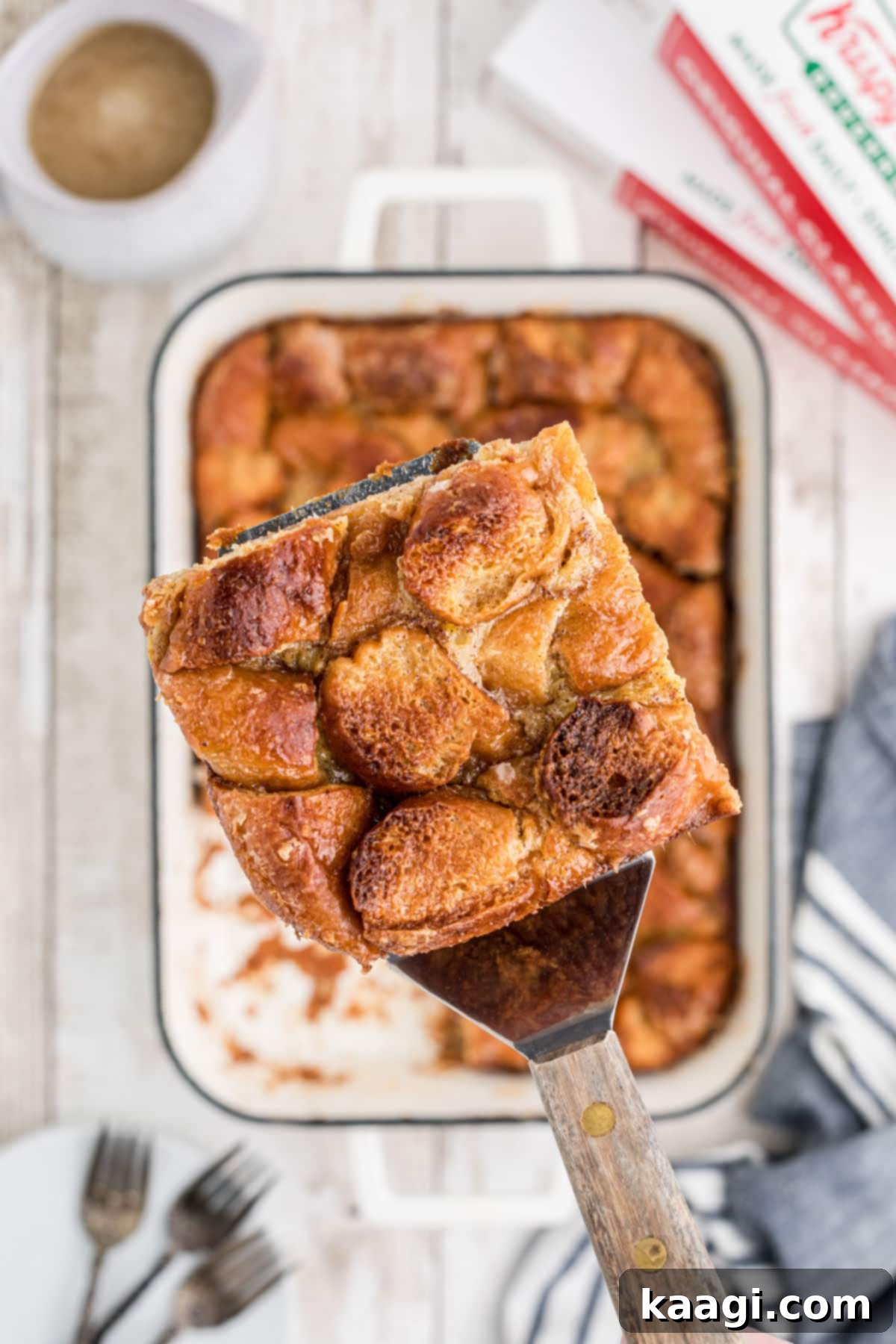 A serving of Krispy Kreme bread pudding being carefully lifted out of the baking dish, highlighting its soft, custardy texture.