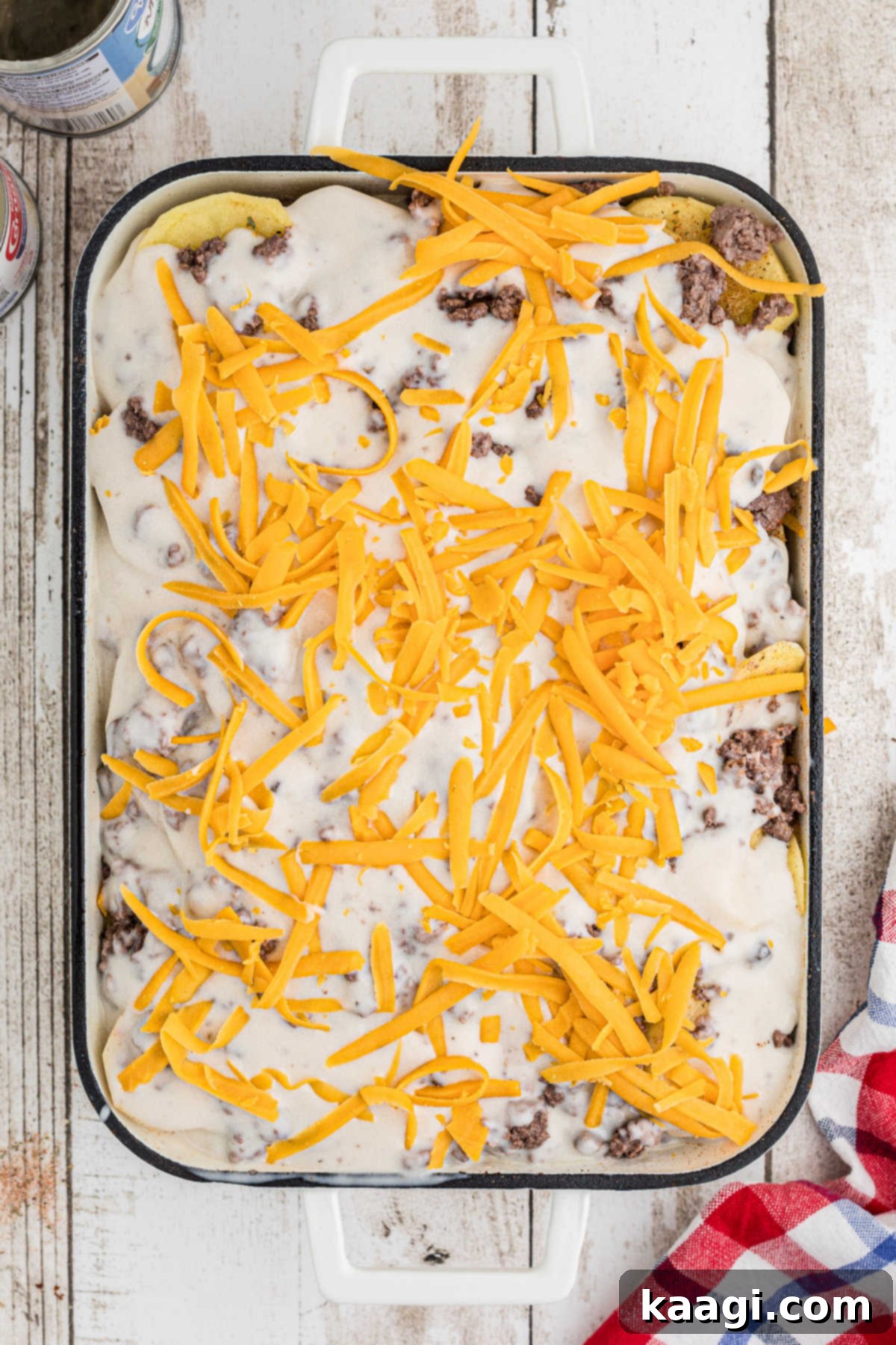 Homestyle Beef and Potato Casserole 11 The top of the casserole generously covered with shredded cheese, prepared for baking and forming a golden crust.