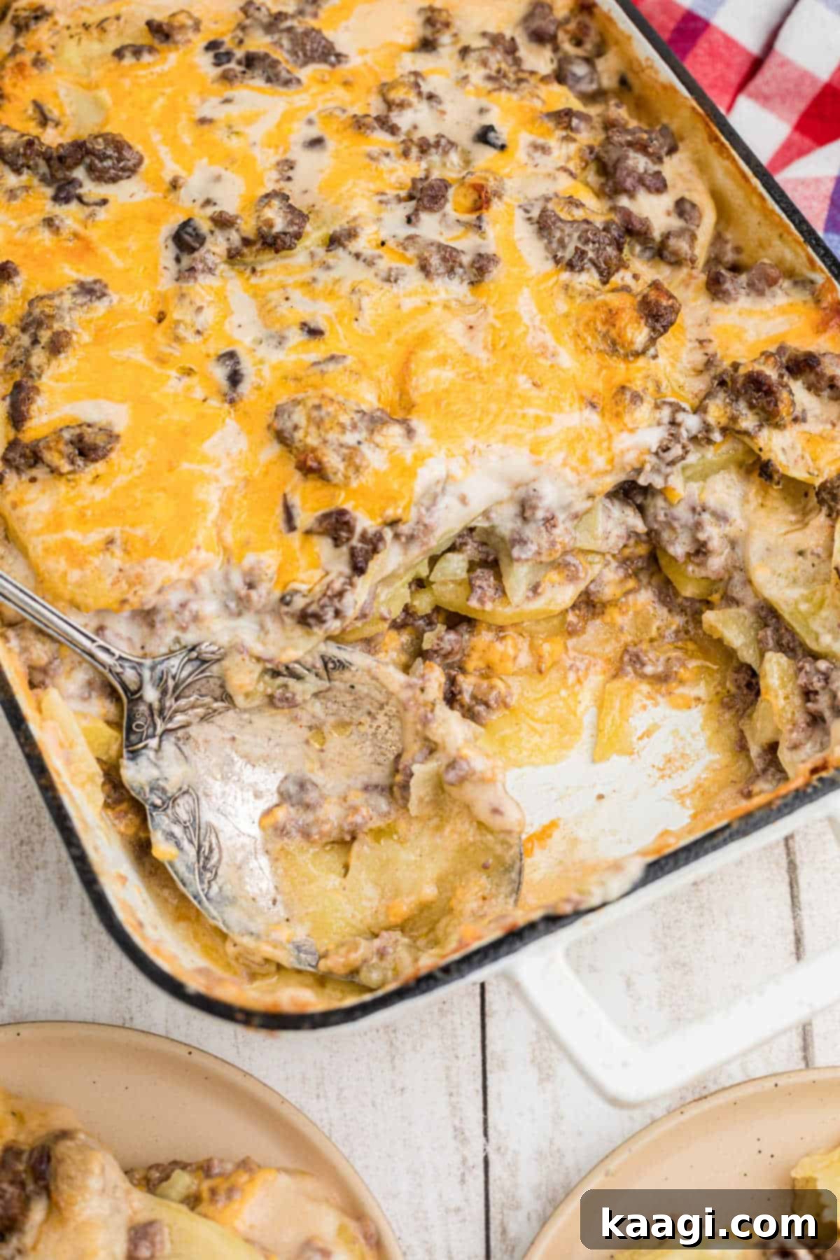 Homestyle Beef and Potato Casserole 12 An overhead portrait view of a delectable hamburger potato casserole, with a section scooped out and a spoon resting nearby, inviting you to take a bite.
