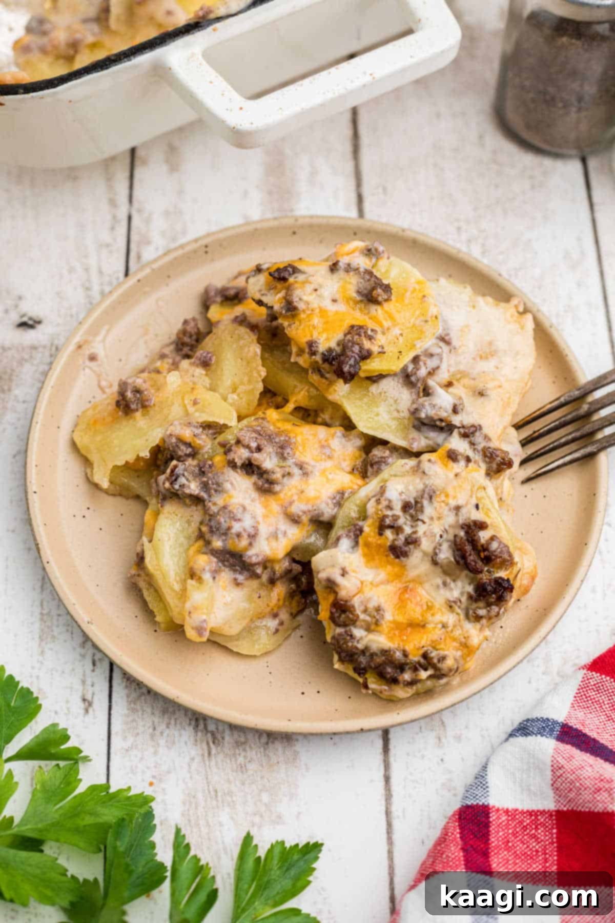 Homestyle Beef and Potato Casserole 14 A beautifully plated serving of hamburger potato casserole with a fork poised, ready for a delicious bite, showcasing its golden-brown top and tender layers.