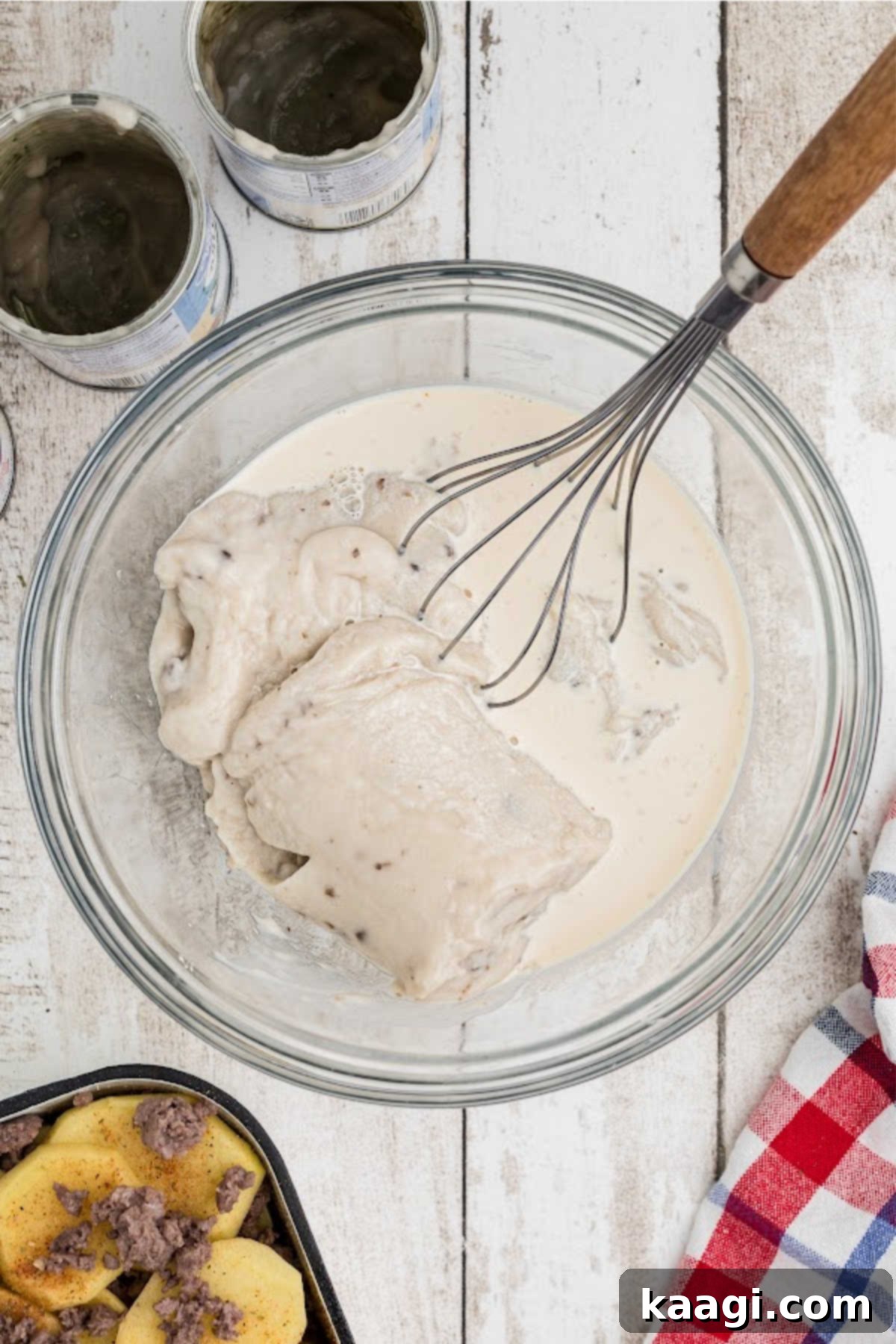 Homestyle Beef and Potato Casserole 10 A large mixing bowl containing cream of mushroom soup and evaporated milk being whisked together, creating the creamy sauce for the casserole.