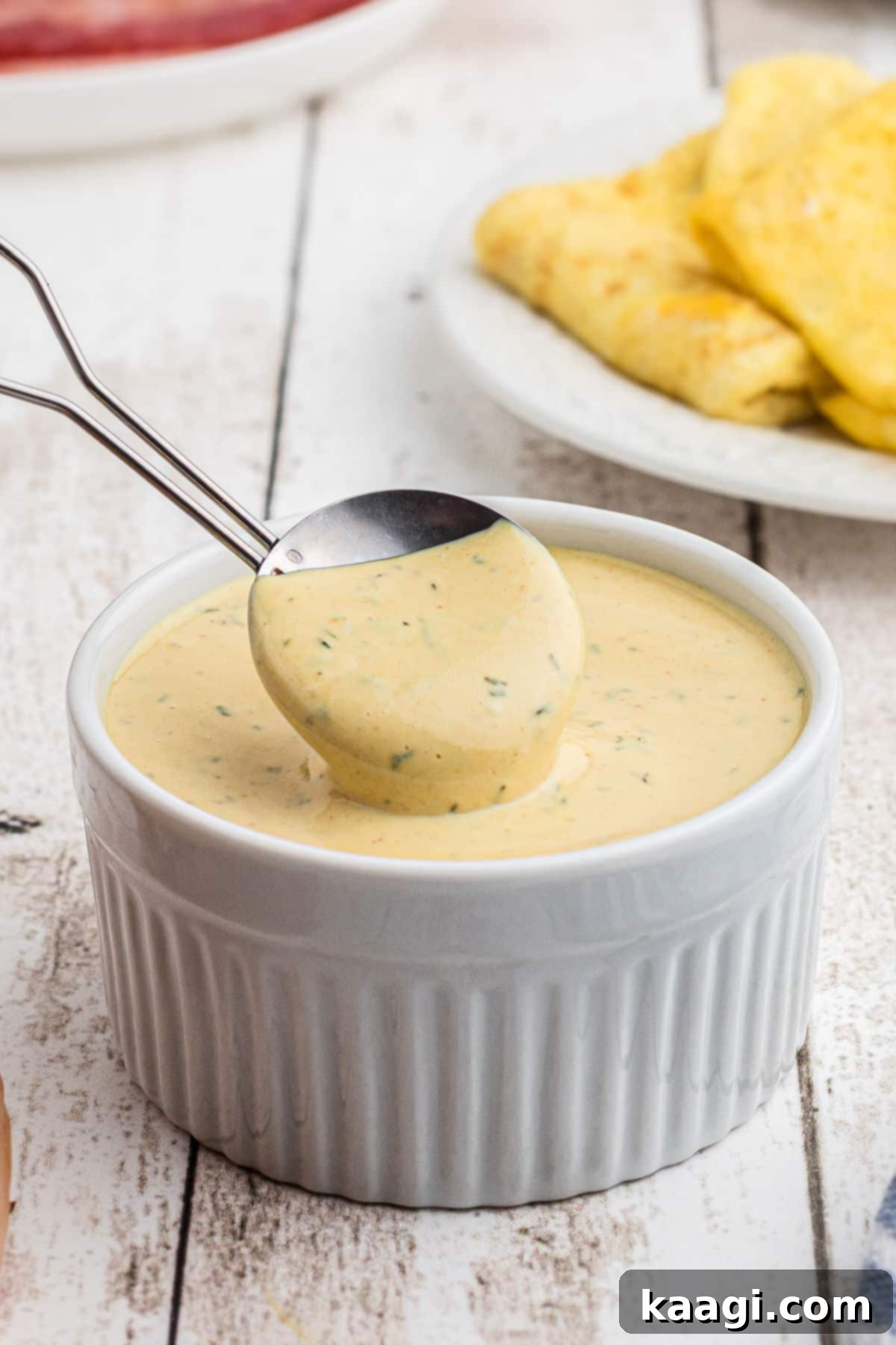 Close up shot of a bowl of homemade copycat McDonald's breakfast sauce with a spoon for serving.