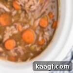 Tender Slow Cooker Rabbit Stew 7 Overhead close up view of a slow cooker rabbit stew, showing the rich broth, tender meat, and vegetables.