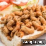 Close up of fried crawfish on a bread dressed with lettuce tomatoes and mayonnaise.