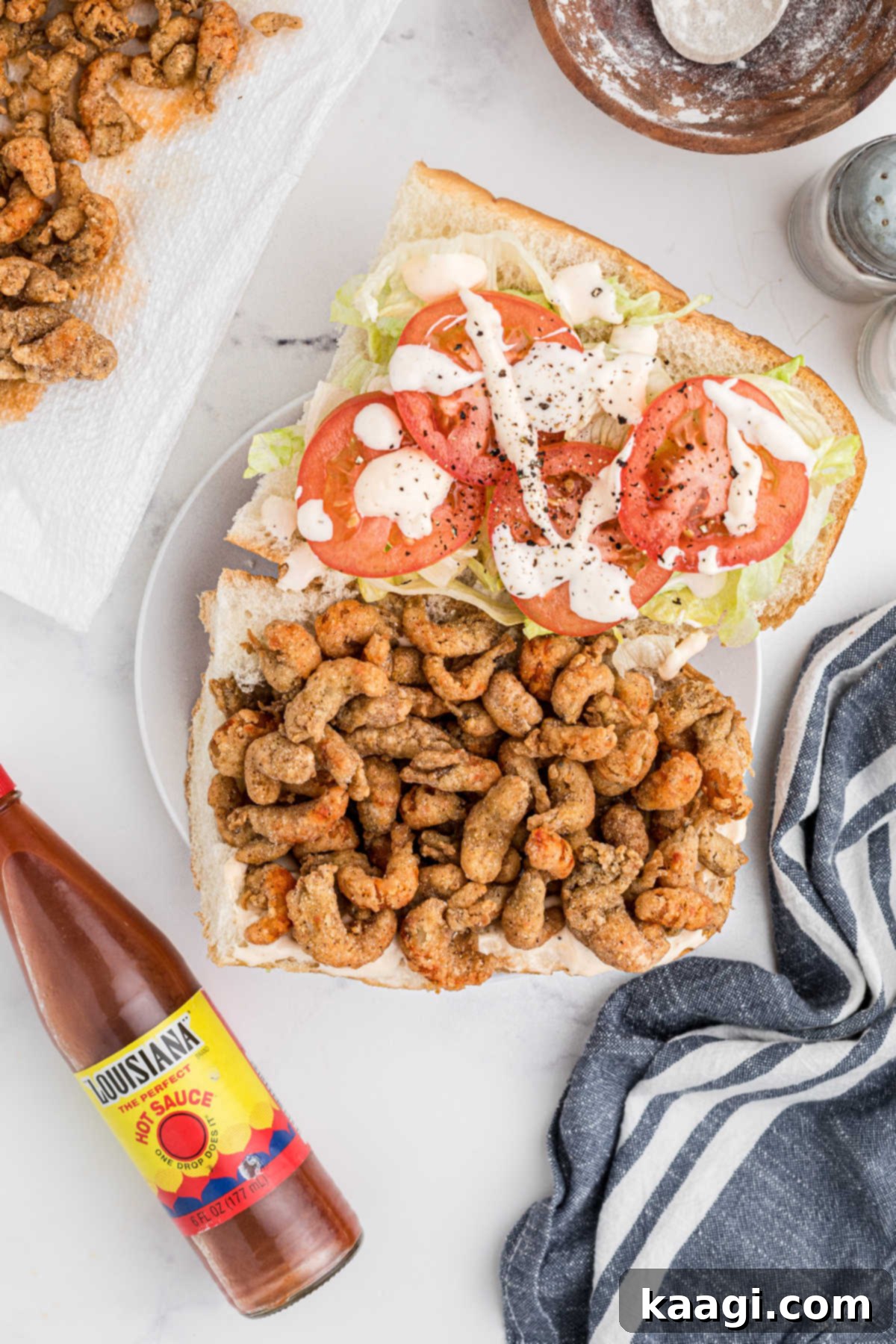 A po boy sandwich being dressed and filled with fried crawfish.