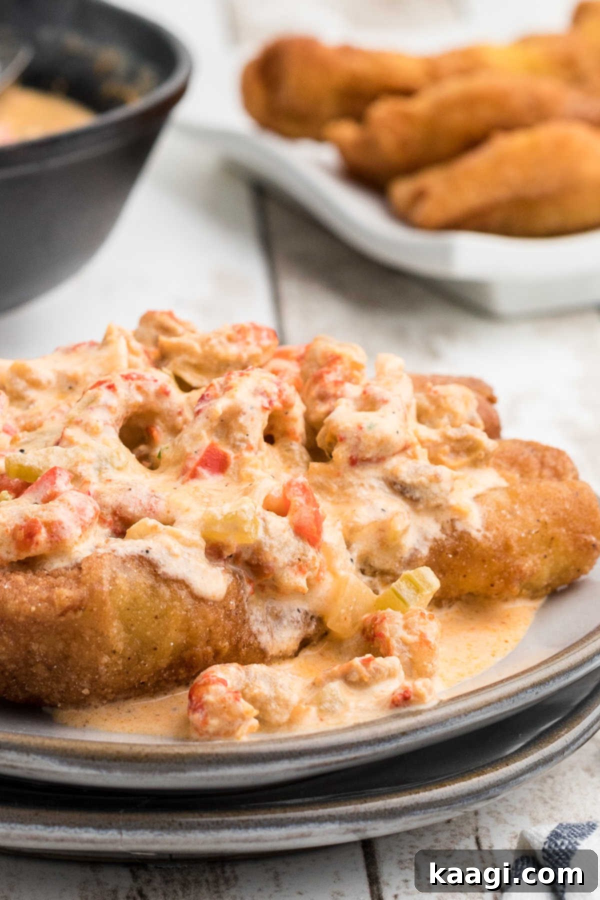 Very close up side view of crawfish sauce poured generously over a piece of crispy fried fish, highlighting its creamy texture and inviting presentation.