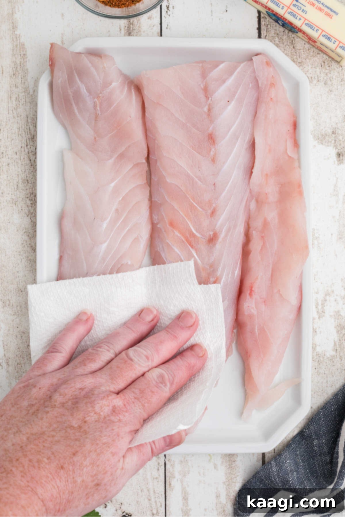 Smoky Cajun Redfish 4 A plate full of redfish fillets, being patted dry with some paper towel. This critical step ensures a crispy, flavorful crust.