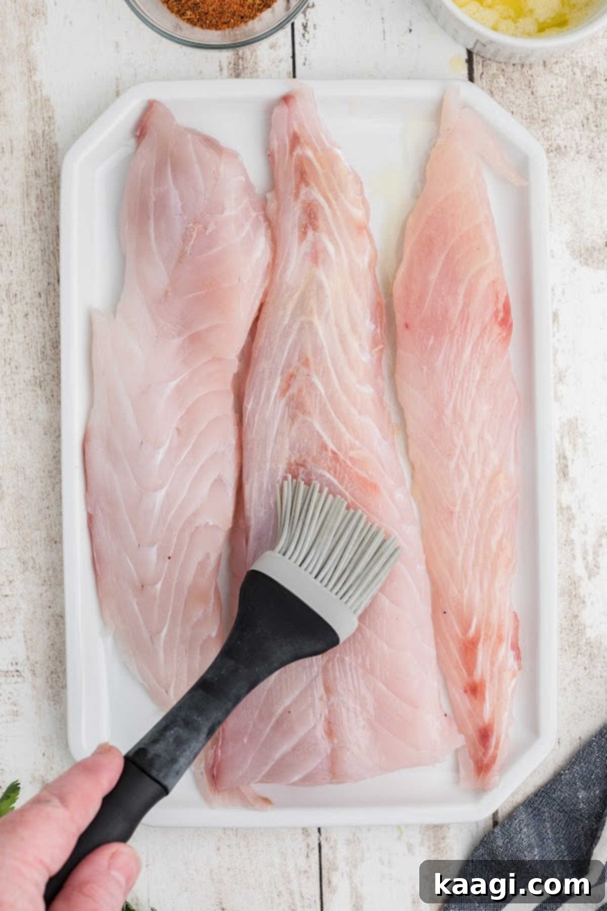 Smoky Cajun Redfish 5 Melted butter being generously brushed onto some redfish fillets, creating a perfect base for the blackening seasoning.