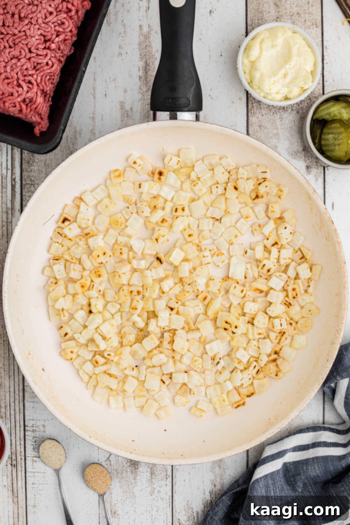 Ultimate Big Mac Comfort Casserole 4 Overhead shot of a large skillet filled with onions, cooking.