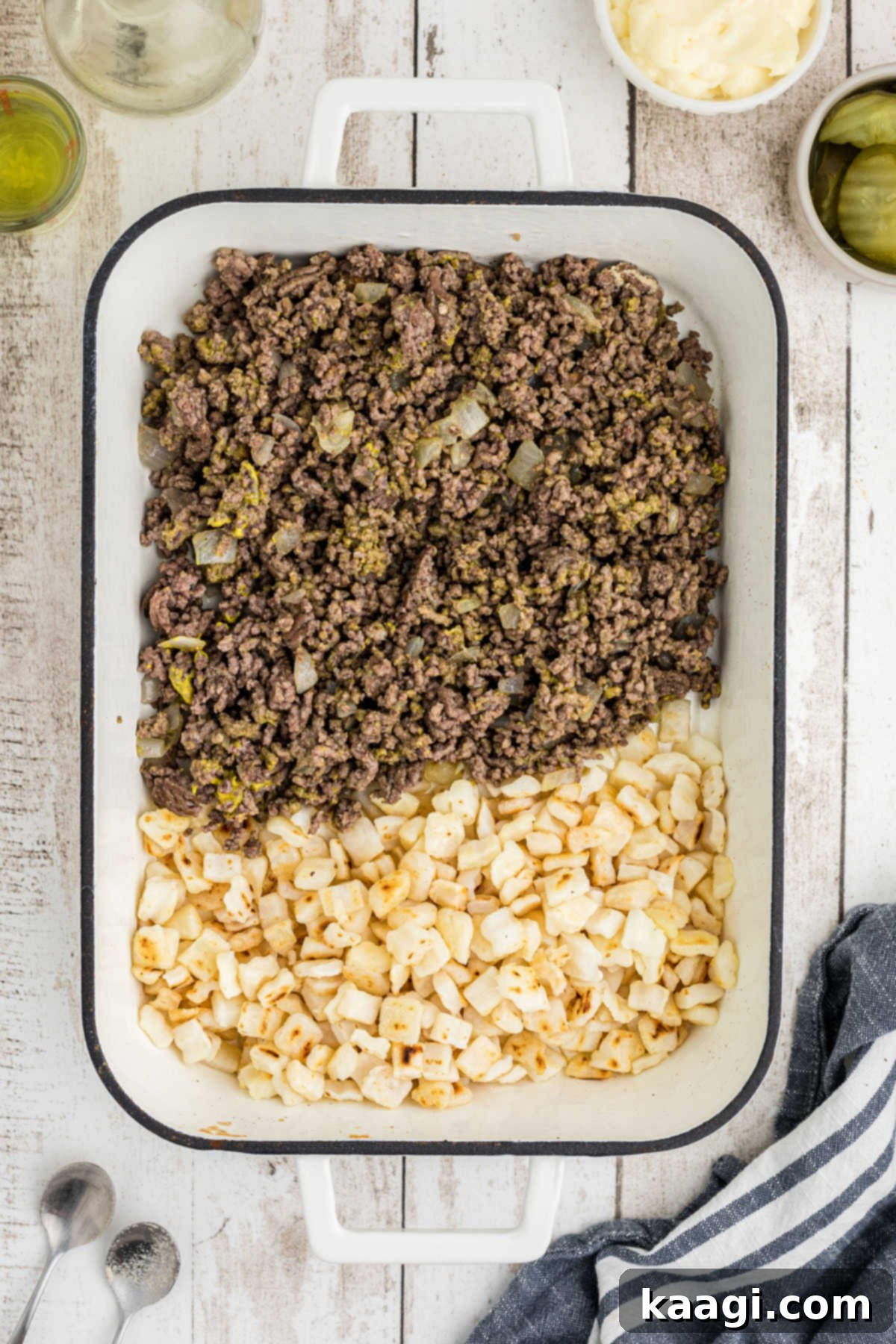 Ultimate Big Mac Comfort Casserole 7 An overhead view of a casserole dish filled with cooked ground meat and hash brown potatoes.