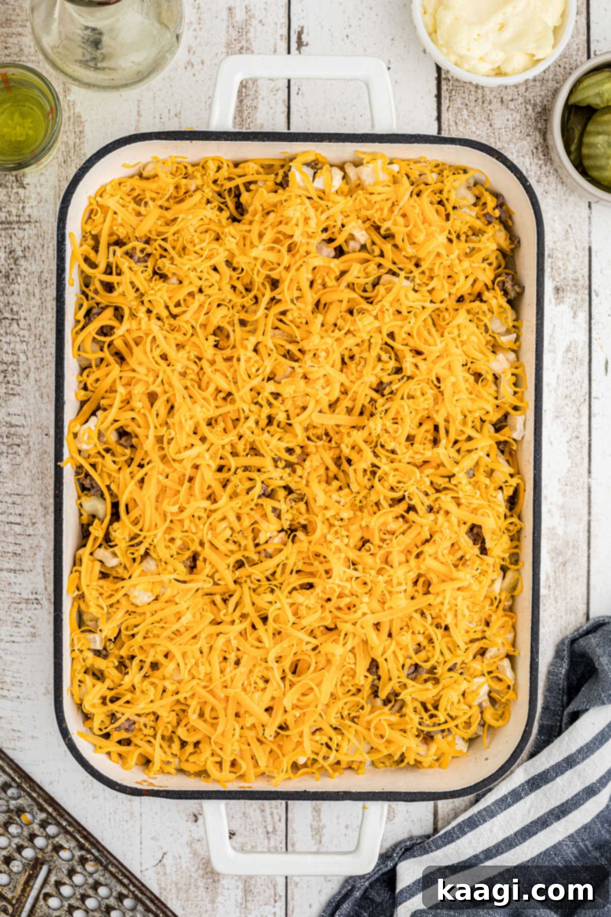 Ultimate Big Mac Comfort Casserole 8 An overhead view of a casserole dish filled with ground meat and cheese sprinkled on top.