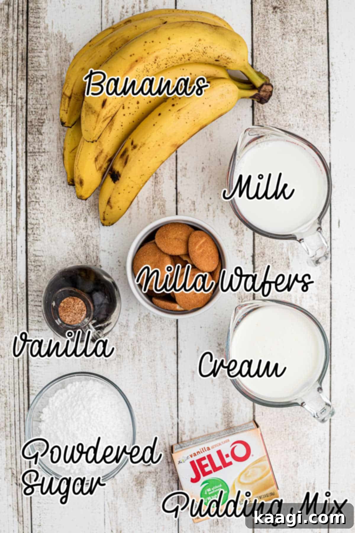A flat lay of ingredients for banana pudding cups, including instant pudding mix, milk, heavy cream, powdered sugar, vanilla extract, bananas, and vanilla wafers.