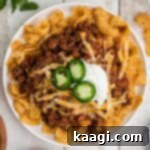 Overhead shot of a plate full of crockpot Frito pie, garnished with cheese and sour cream.