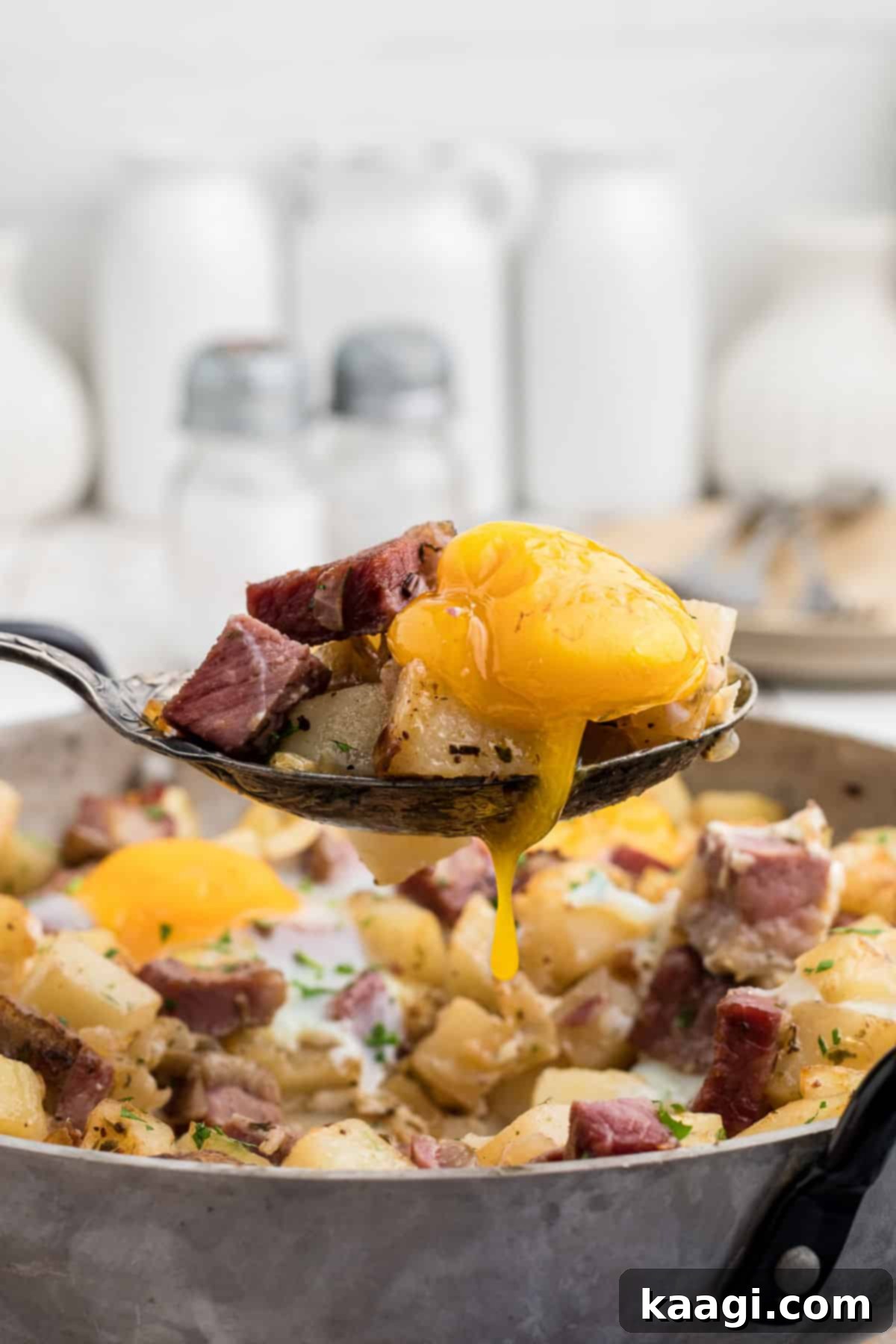Close up of a spoon digging into a traditional Irish corned beef hash recipe, showcasing the crispy potatoes, tender corned beef, and perfectly cooked eggs.