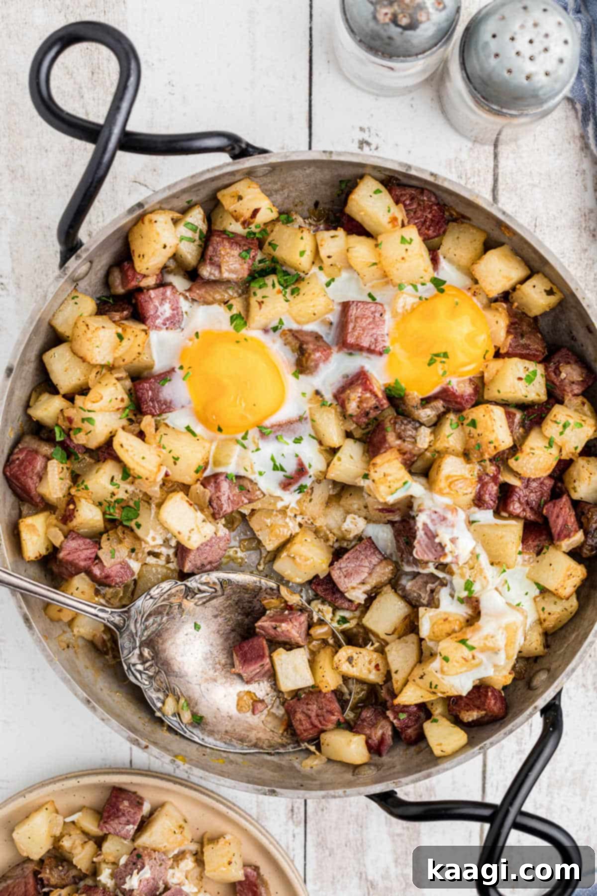 Overhead shot of a skillet with a freshly cooked traditional Irish corned beef hash with a spoon digging in, showing the texture and ingredients.