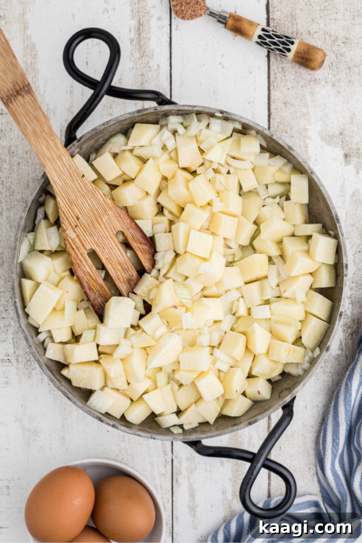 A skillet filled with melted butter, cubed potatoes, and diced onions sizzling gently, beginning to cook.