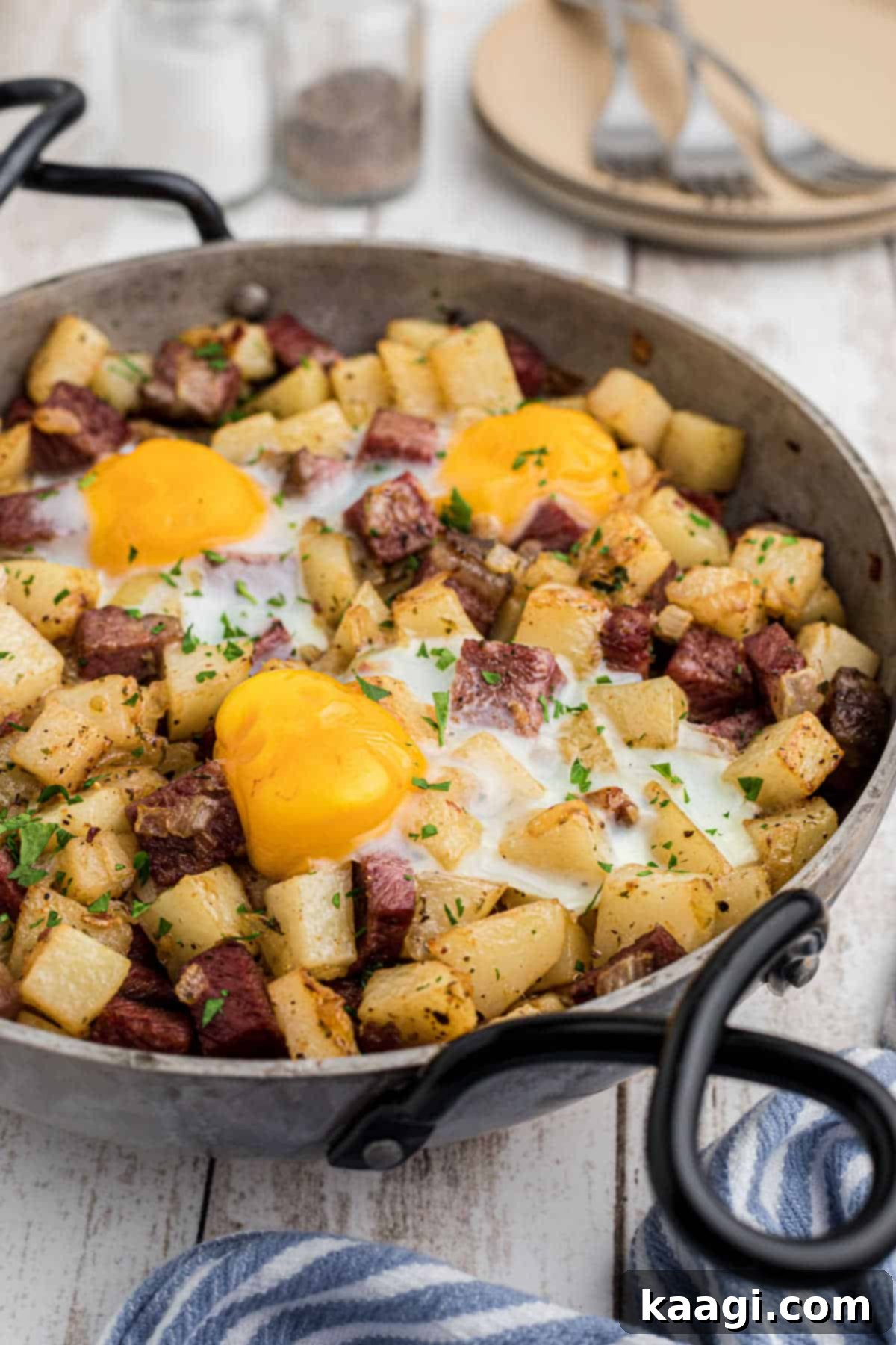 Side view of a pan with golden-brown Irish corned beef hash, topped with sunny-side-up eggs, ready to be served.