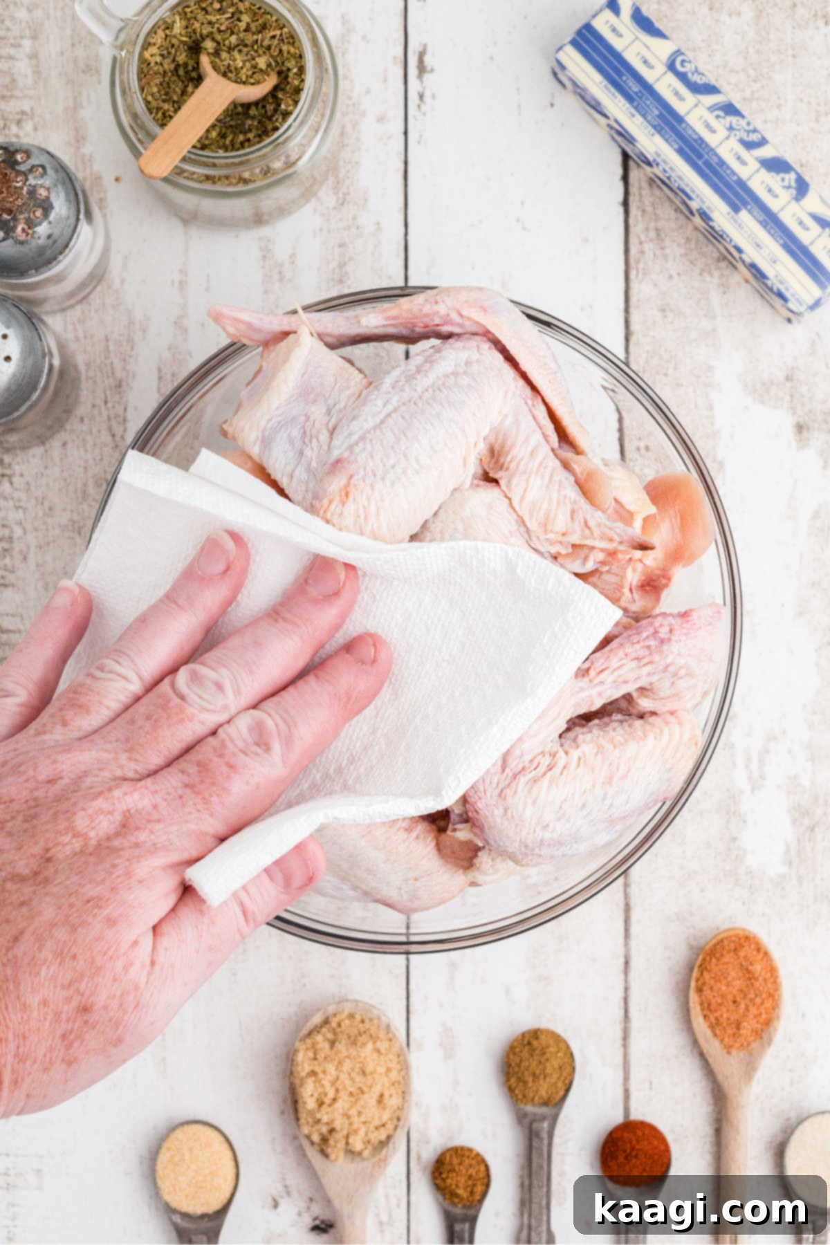 Homemade Wingstop Louisiana Rub 4 A bowl of chicken wings being patted dry with a paper towel, a crucial step for crispy skin.