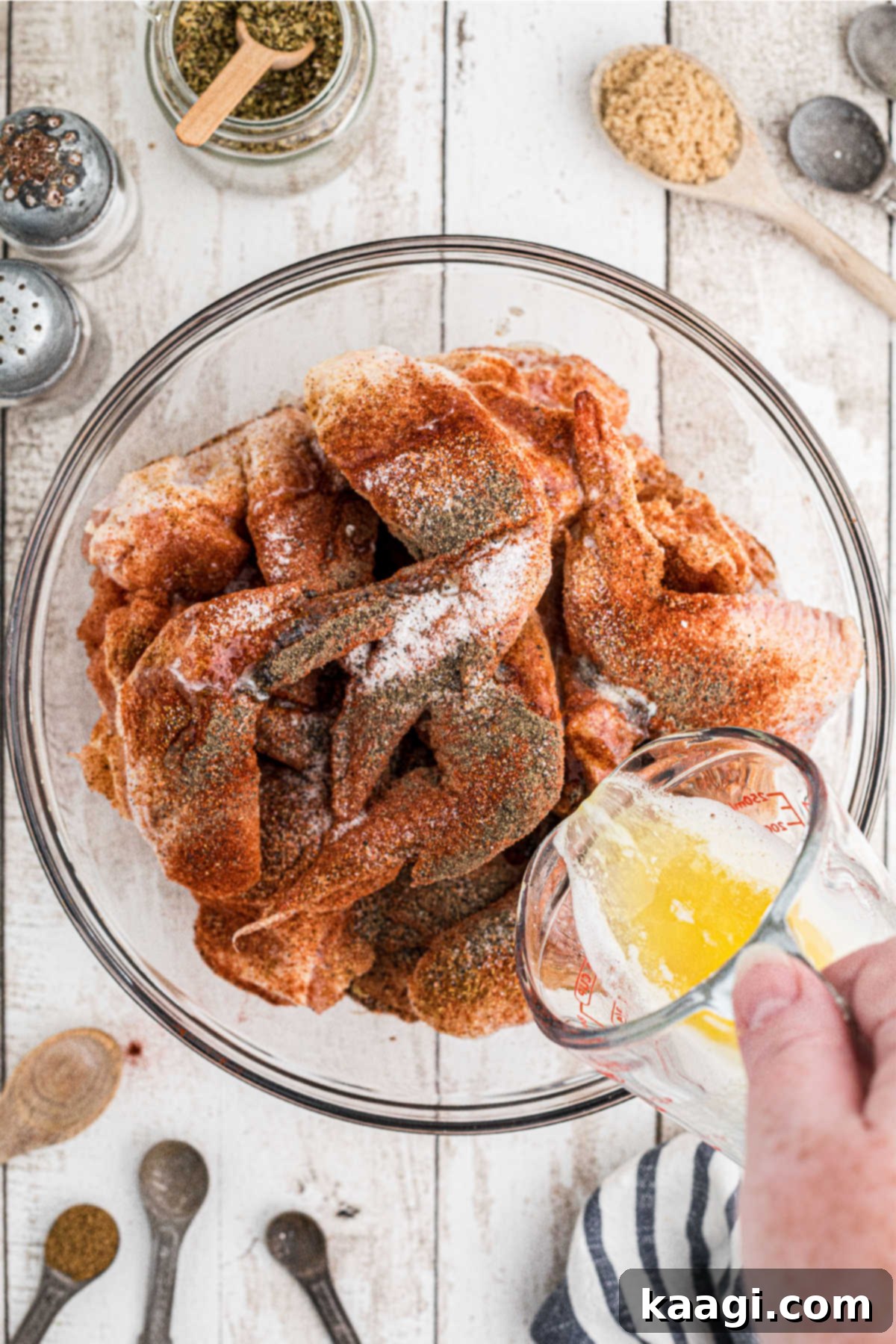 Homemade Wingstop Louisiana Rub 6 Melted butter being poured over the seasoned chicken wings in a bowl.