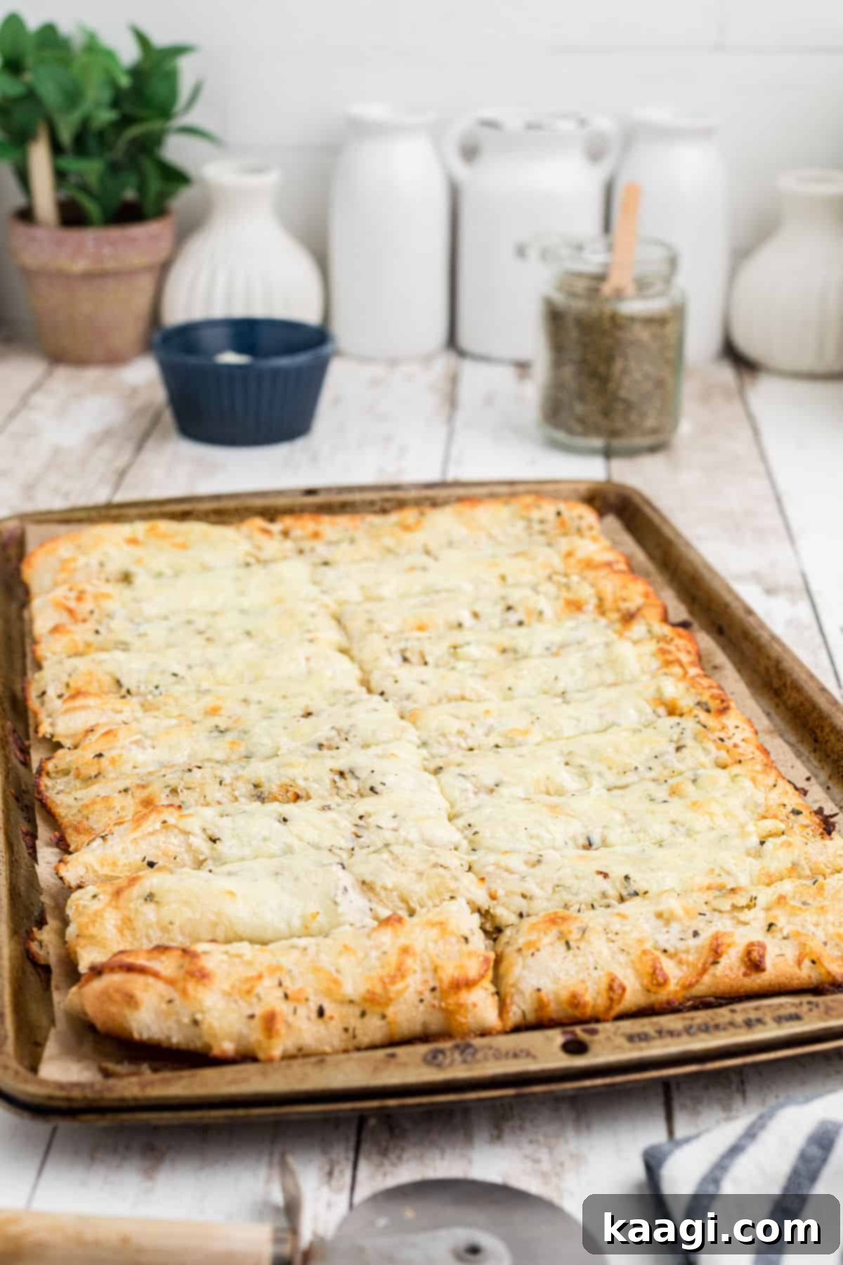 A side view of a large tray filled with freshly baked Italian Cheese Bread sticks, golden and cheesy, ready for serving.