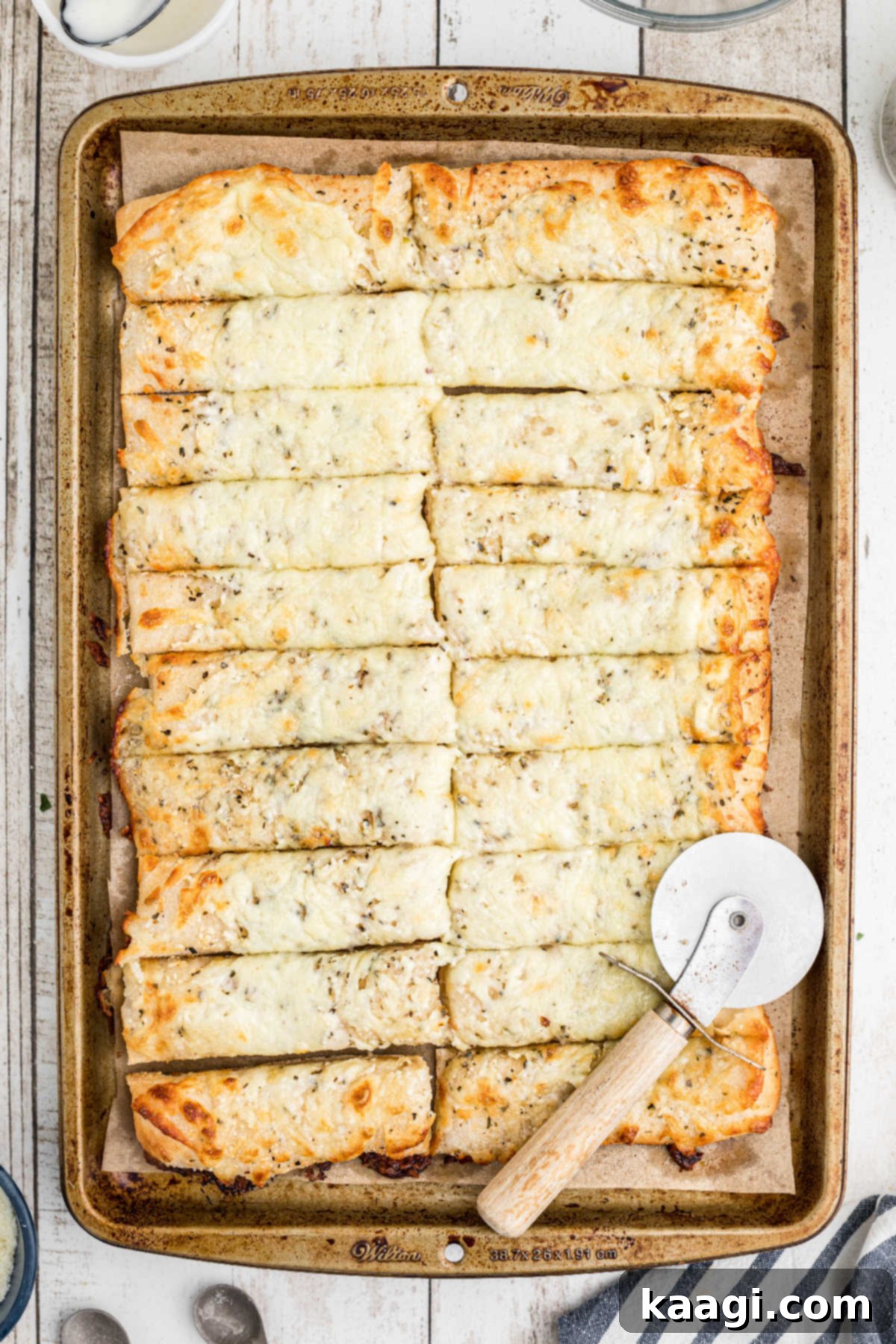The baked Italian cheese bread, sliced into perfect, ready-to-serve rectangular sticks using a pizza wheel.