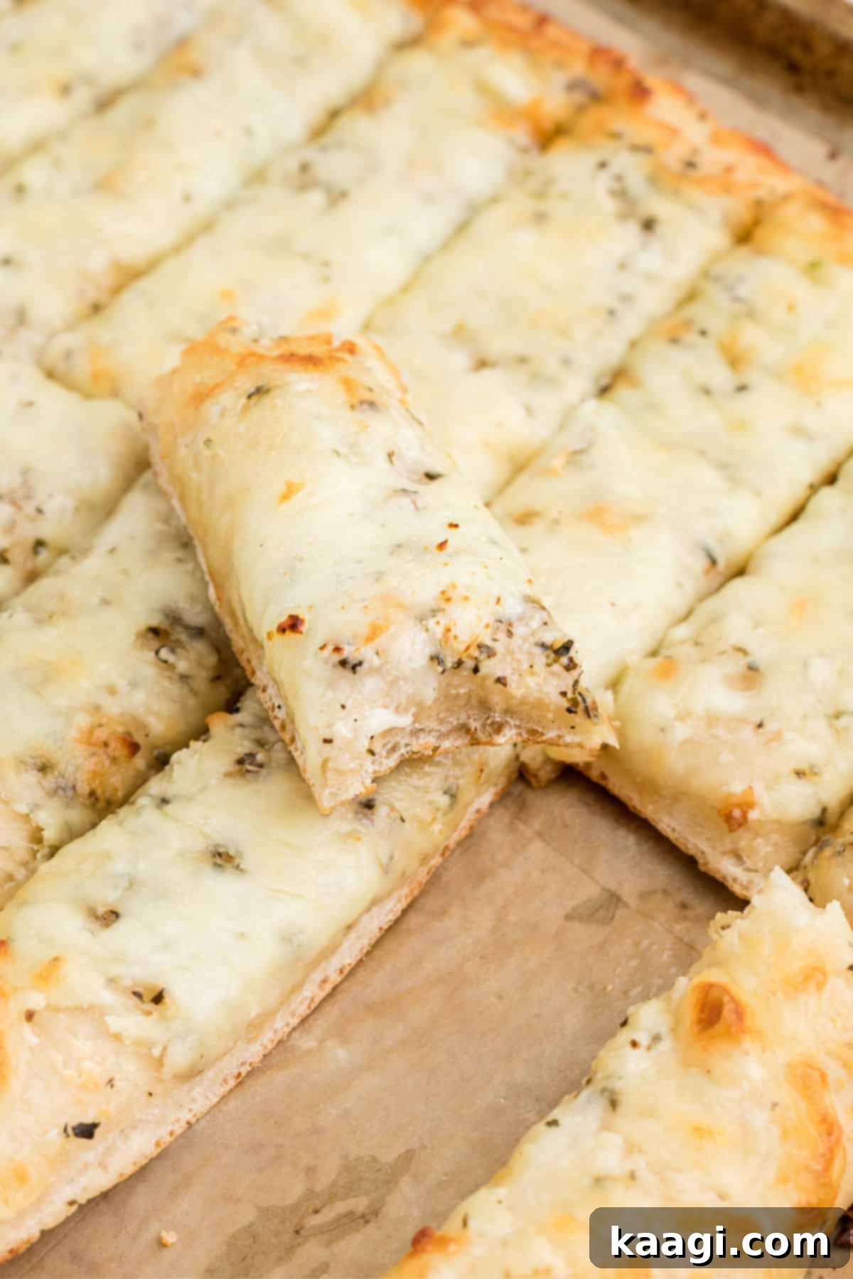 A close-up shot of a piece of Italian Cheese Bread with a bite taken out, showing the gooey melted cheese and airy crust.