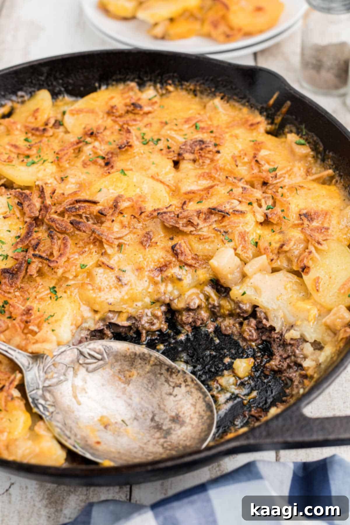 A skillet with a spoon in it, with hobo casserole, ready to be served.