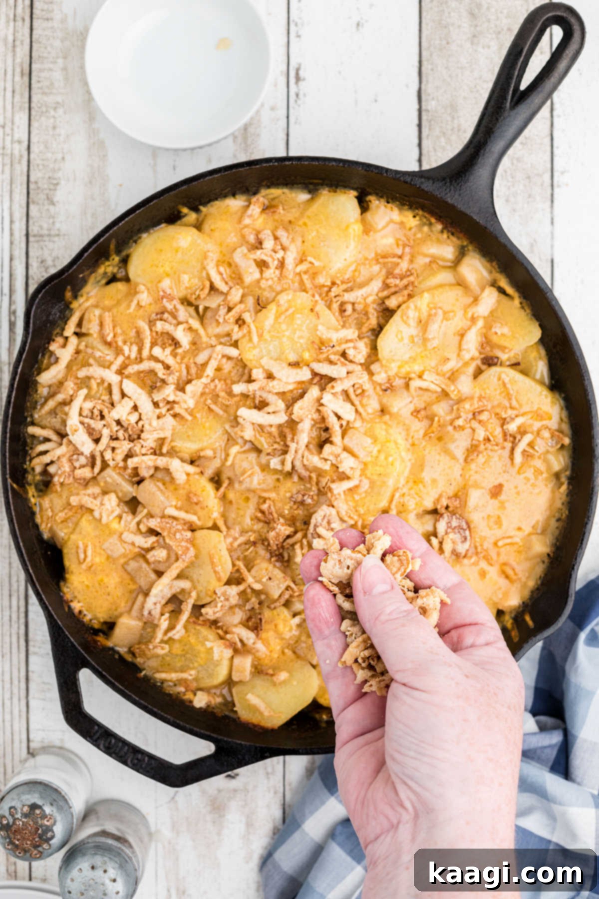 Overhead view of a Hobo Casserole being topped with some crispy French fried onions after baking.