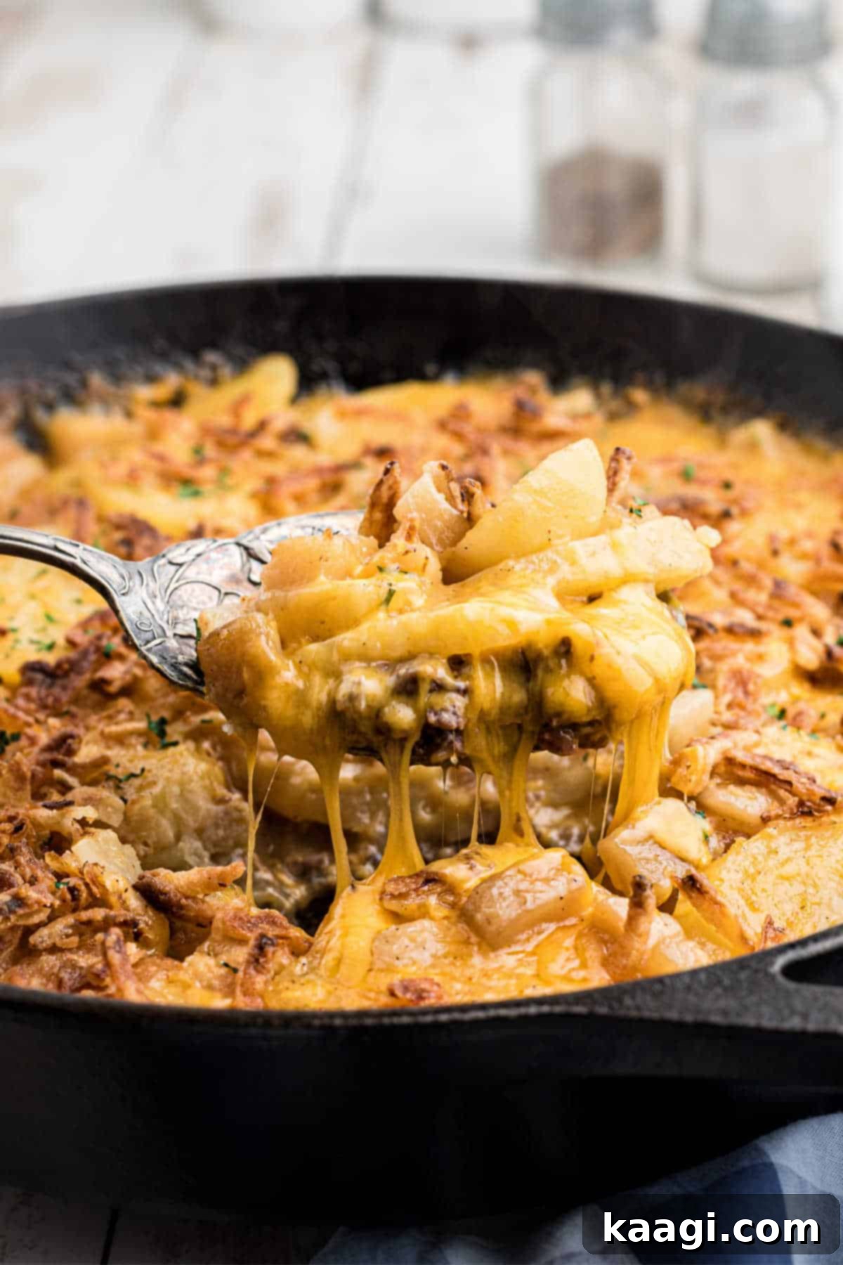 Hobo casserole being scooped out of a skillet with a serving spoon.