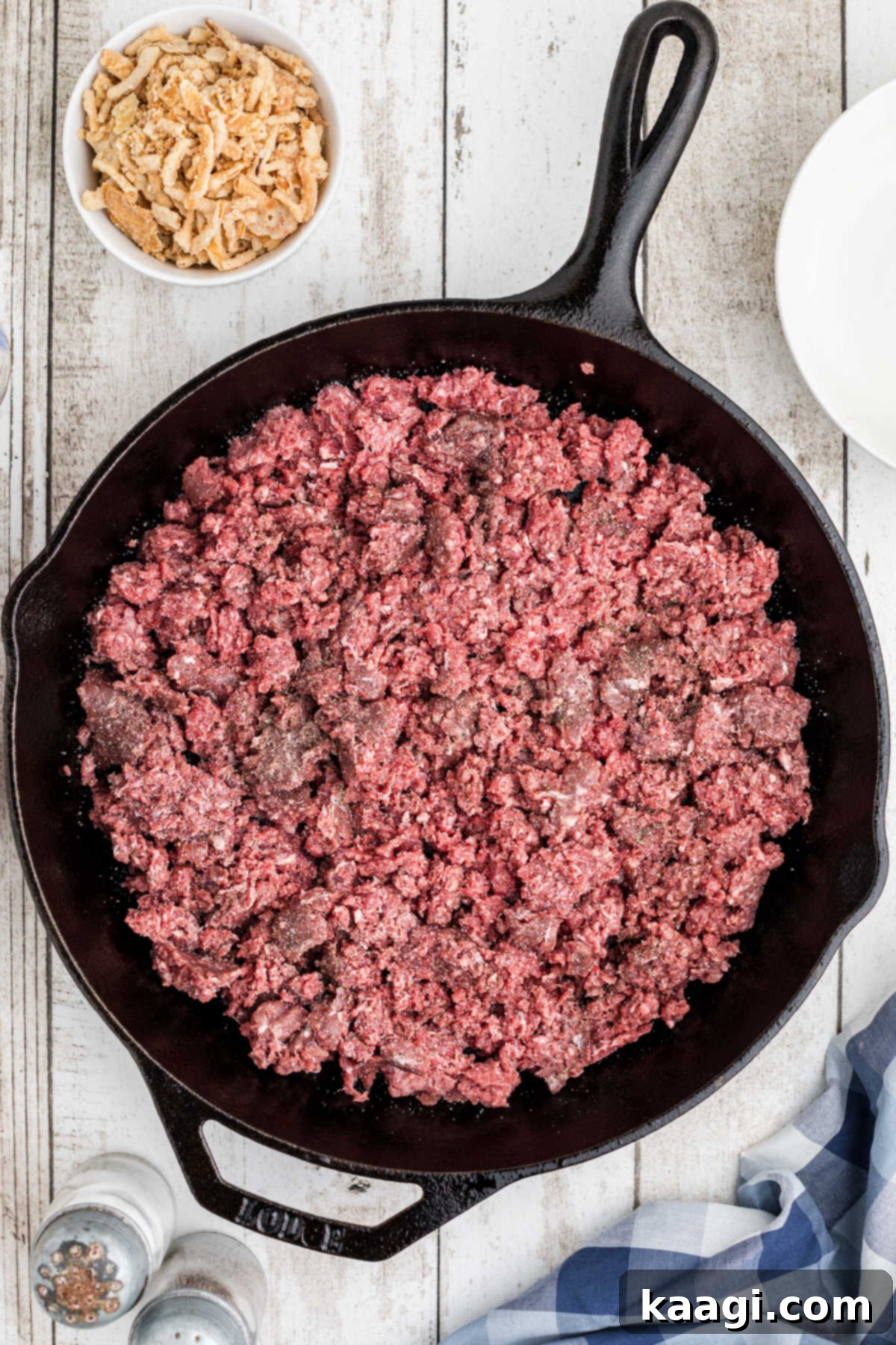 Overhead image of a cast iron skillet with ground beef pressed into the bottom.