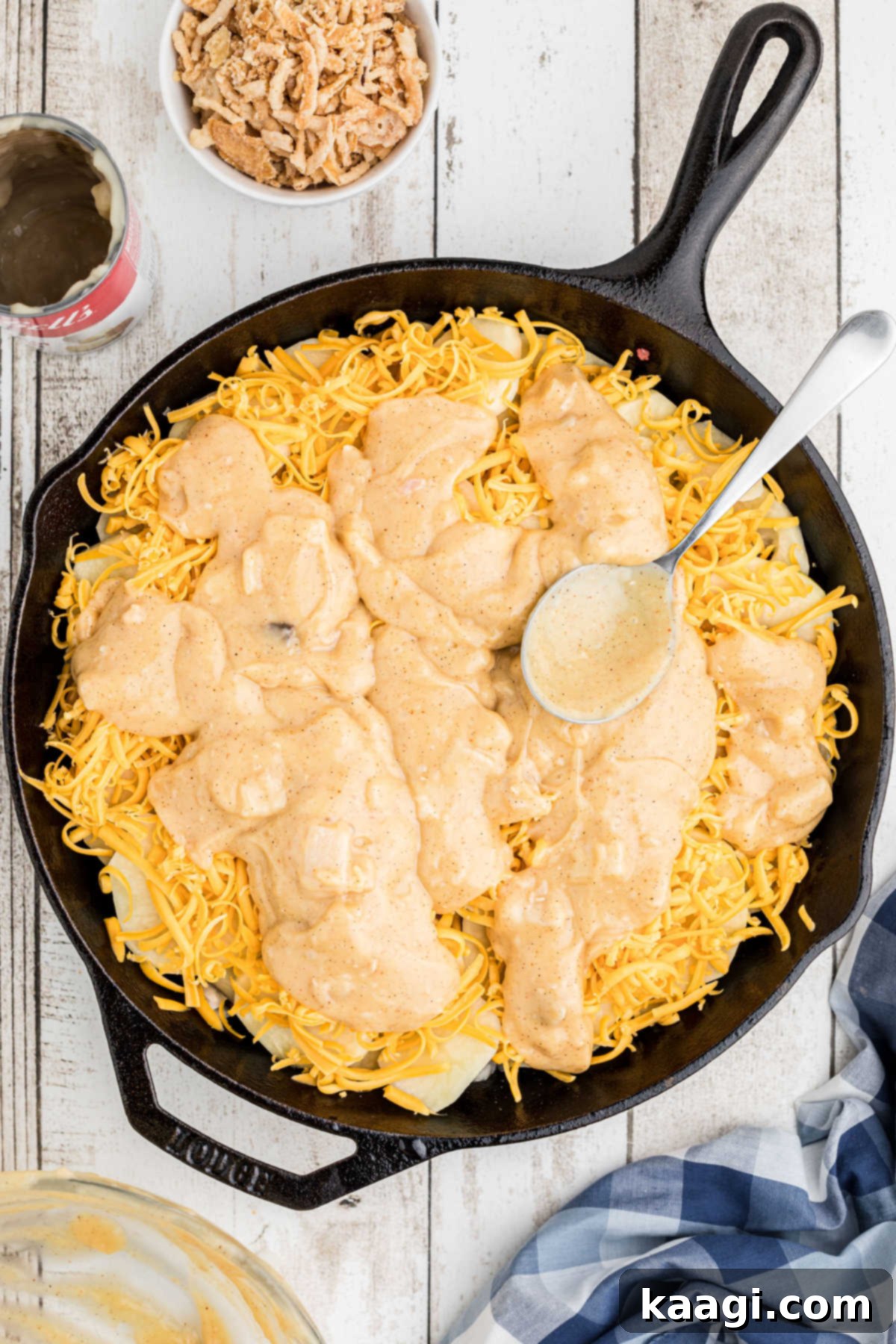 Overhead image of the sauce-like mixture being spread over the cheese layer in the skillet.