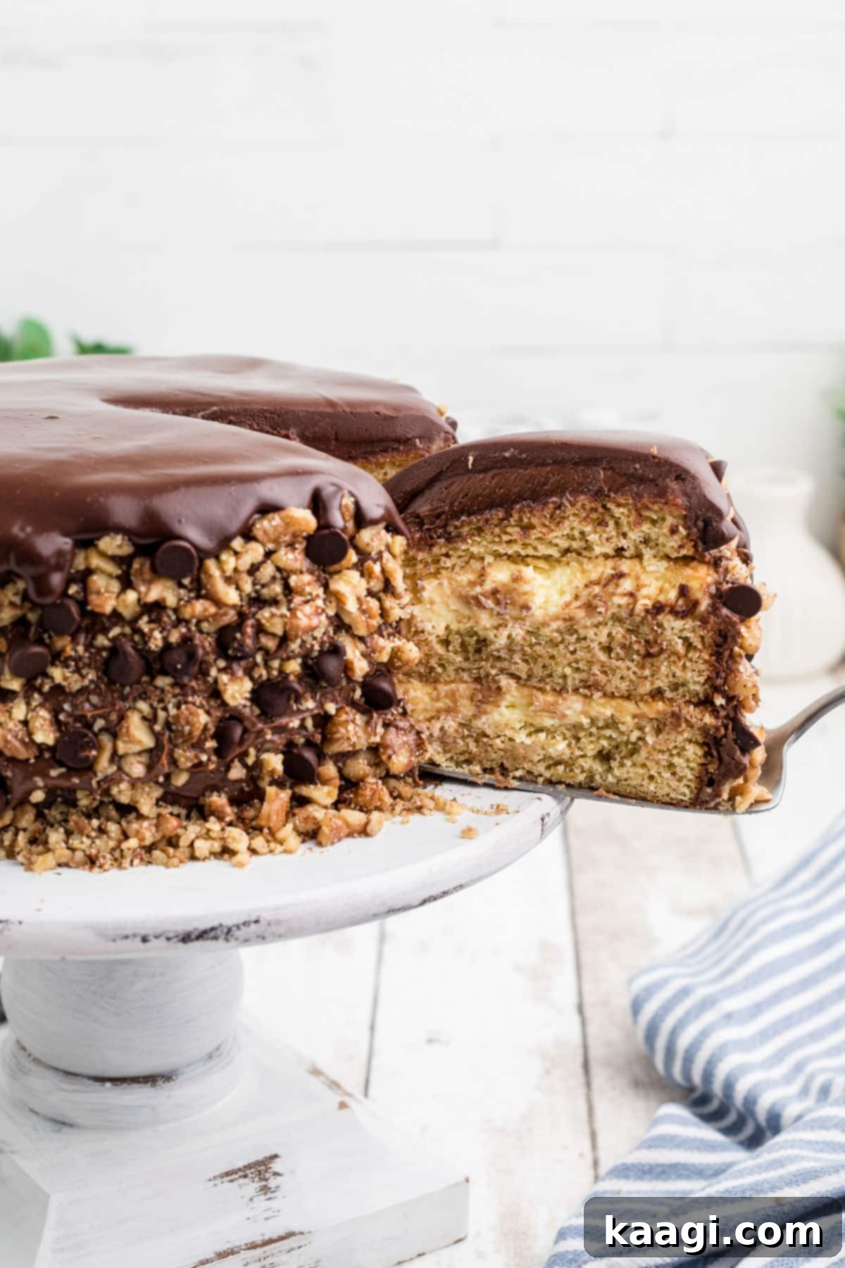 A large slice of Banana Dream Cake being carefully removed from the full cake, highlighting its rich layers and tempting texture.