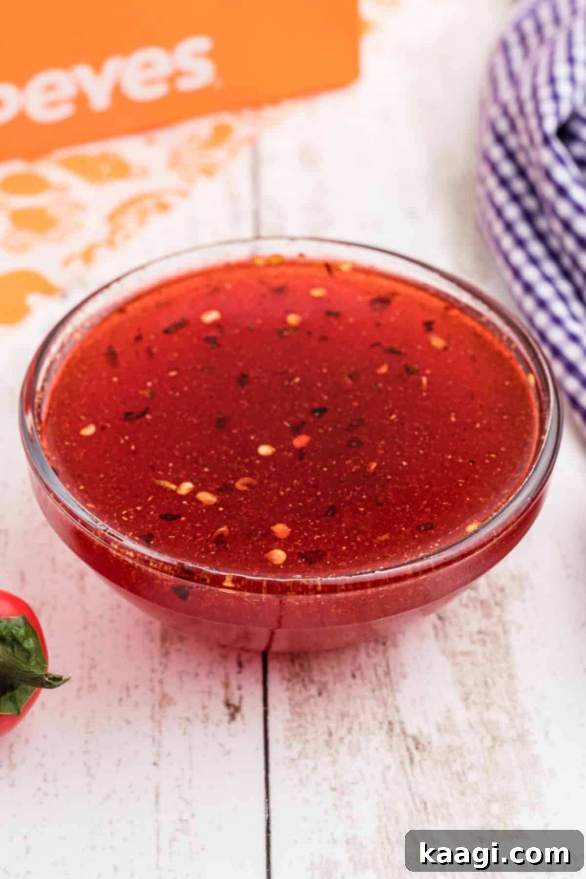 A side shot of a bowl of homemade Popeyes sweet heat sauce, showcasing its vibrant color and texture.
