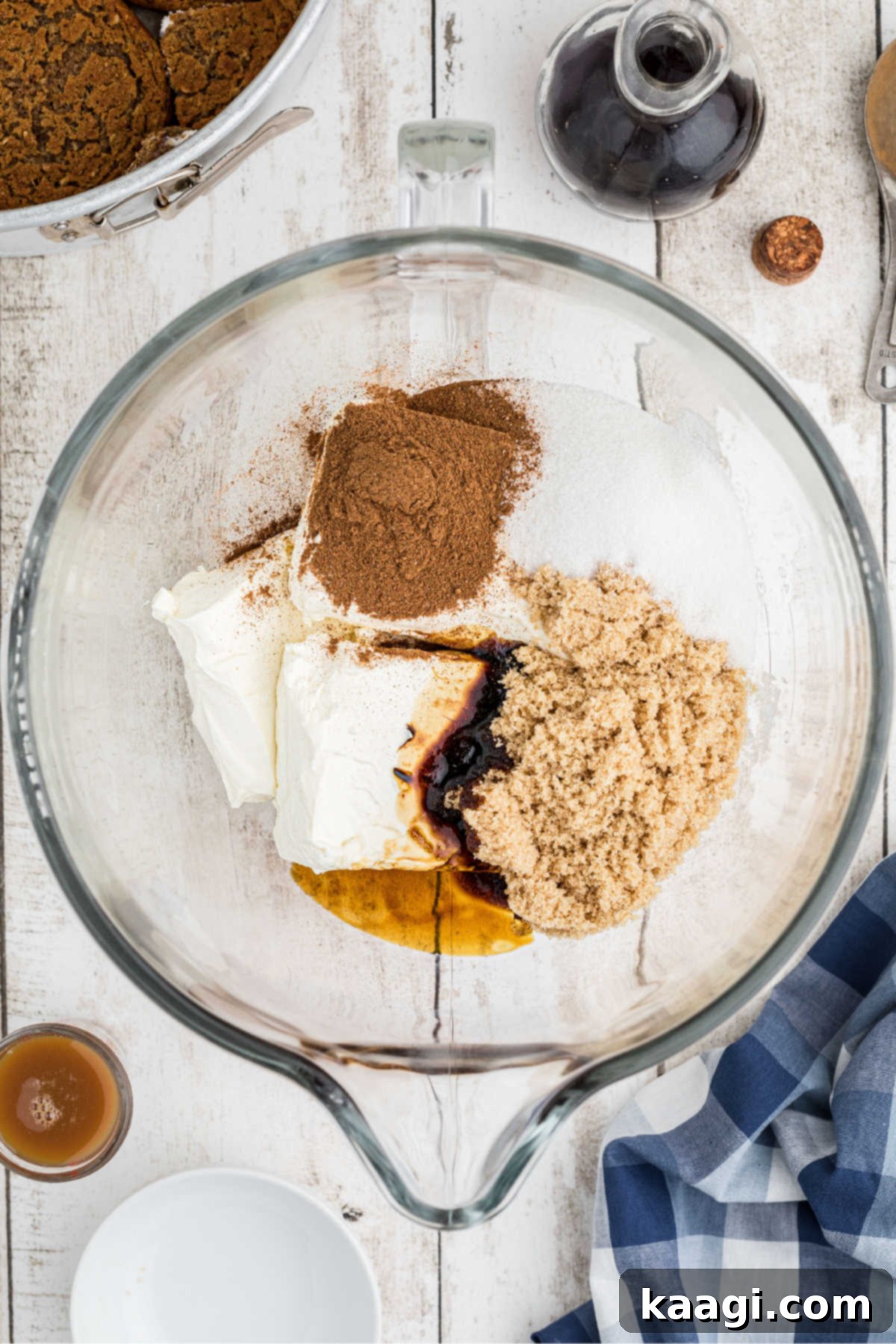 A mixing bowl filled with cream cheese, sugars, and spices, ready to be blended.