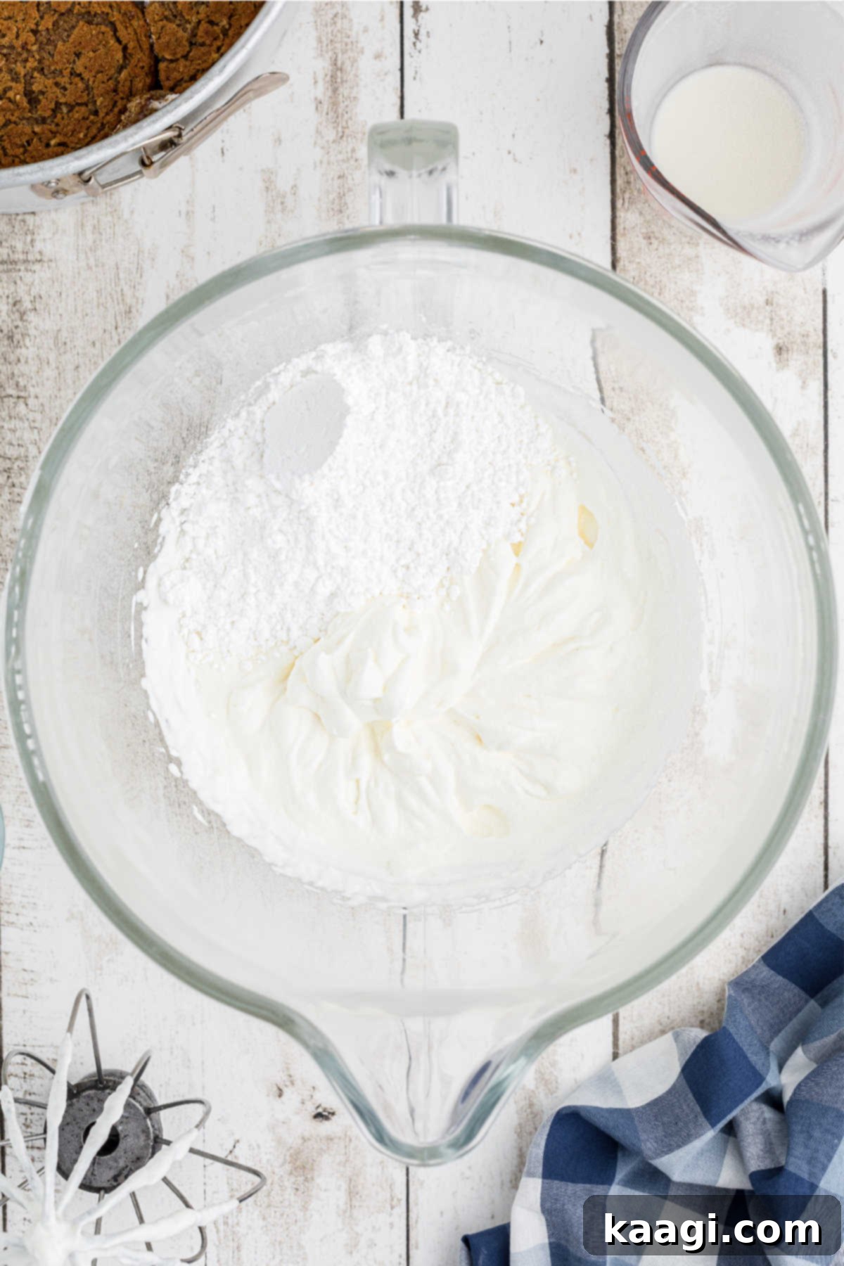 Powdered sugar in a large mixing bowl, next to heavy cream.