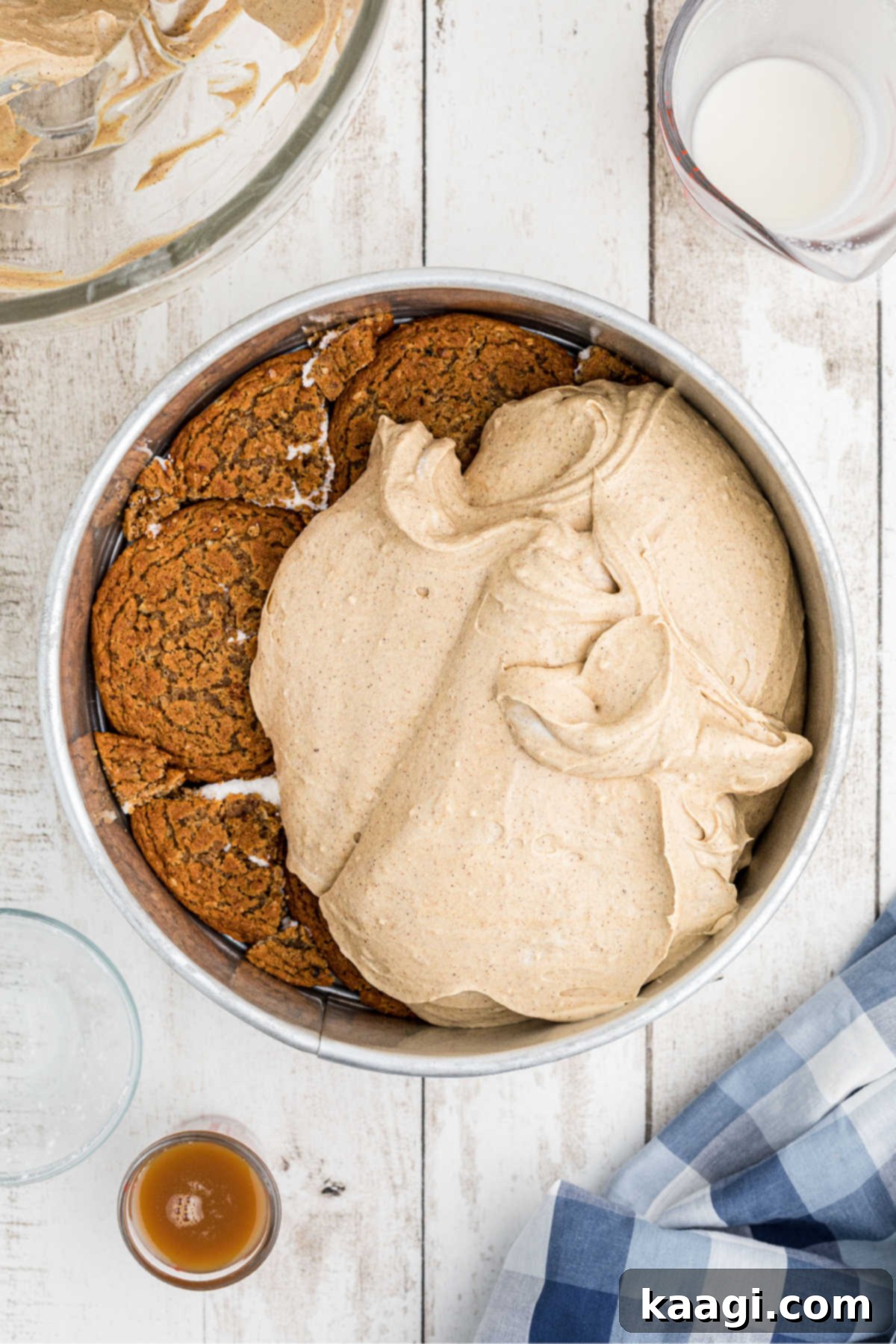 A cream cheese mixture being carefully poured onto an oatmeal creme pie base in a springform pan.