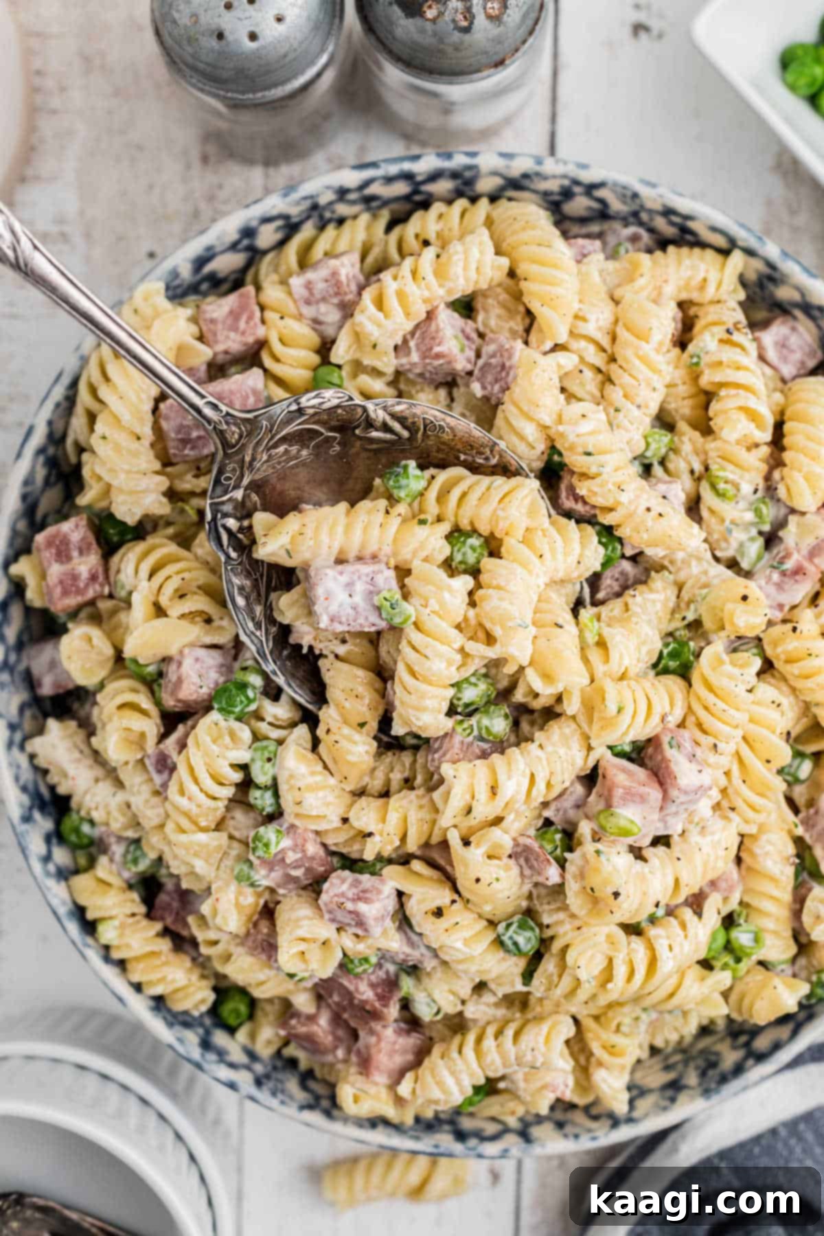 Overhead shot of a bowl of Ruby Tuesday Ham and Pea pasta salad recipe, with a serving spoon.