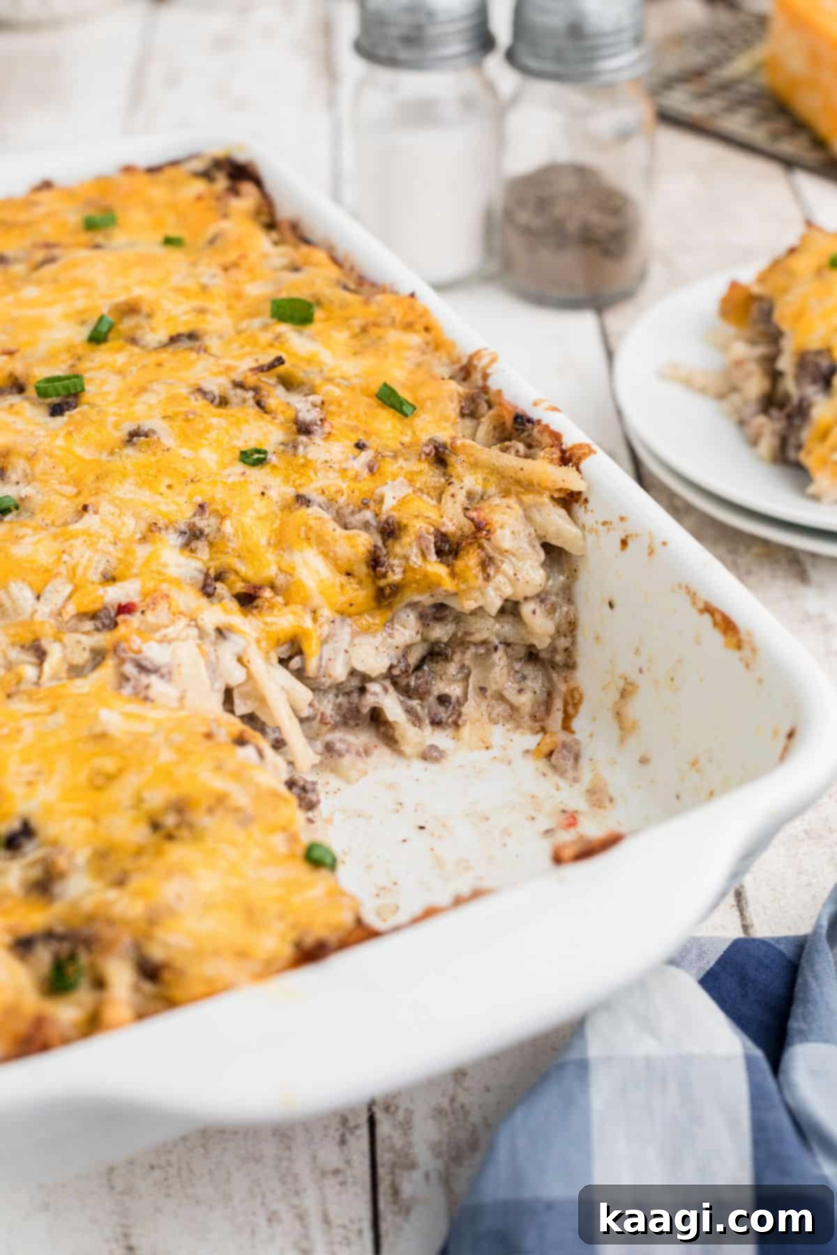 A perfectly baked Hamburger Hashbrown Casserole in a casserole dish, with a portion scooped out, revealing the cheesy, meaty interior.