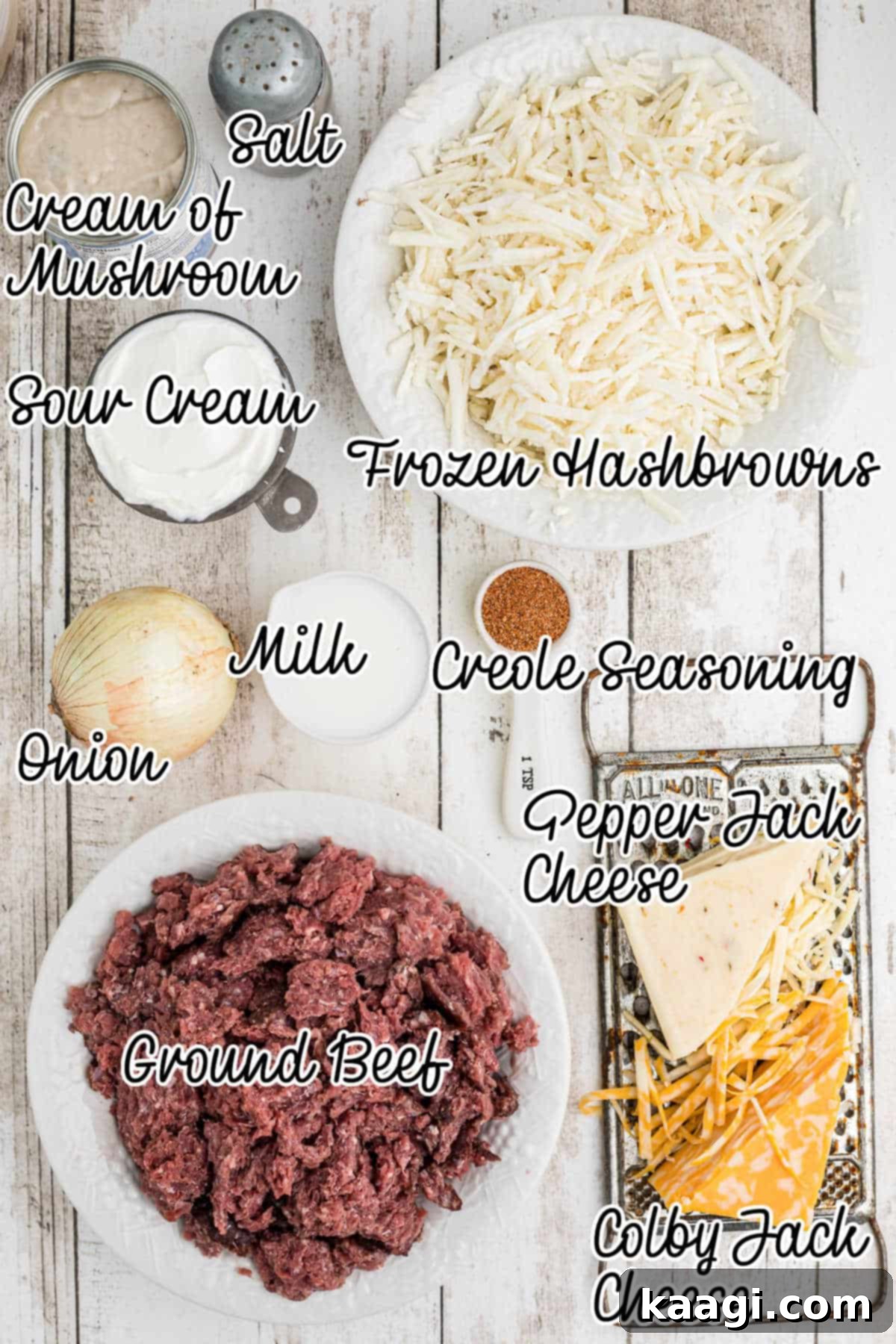 A flat lay of fresh ingredients laid out for a hamburger hashbrown casserole, including ground beef, onions, cheeses, hashbrowns, and condensed soup.