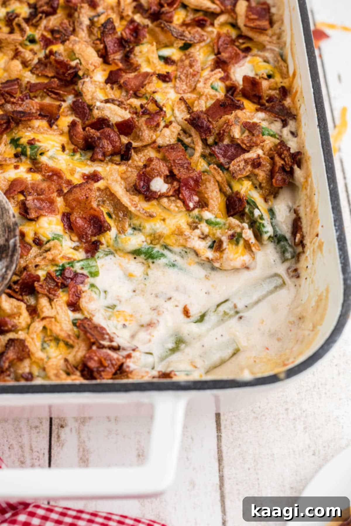 A corner view of a loaded green bean casserole with a scoop missing.