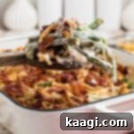 A scoop of loaded green bean casserole being lifted out of the dish.