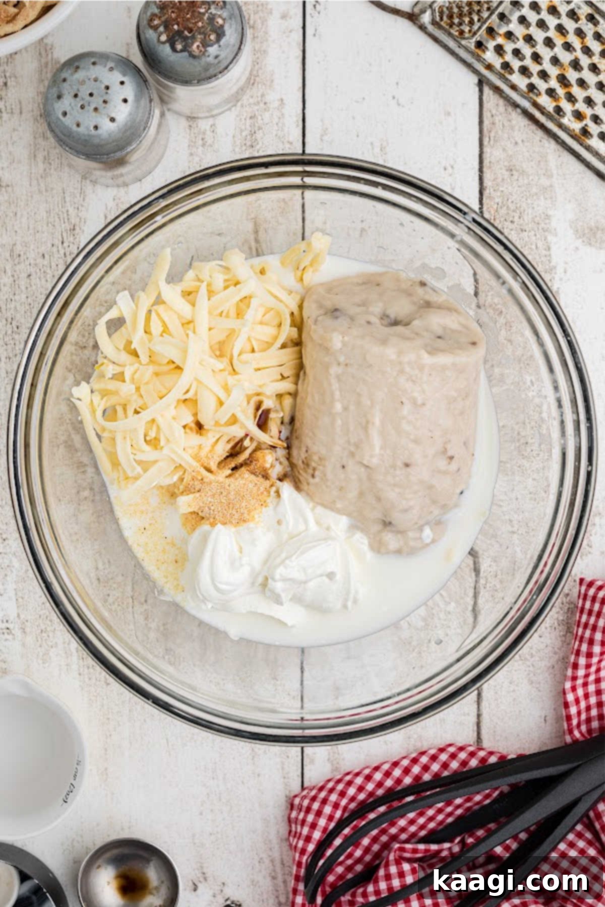 A mixing bowl with mushrooms soup, cheese and milk.